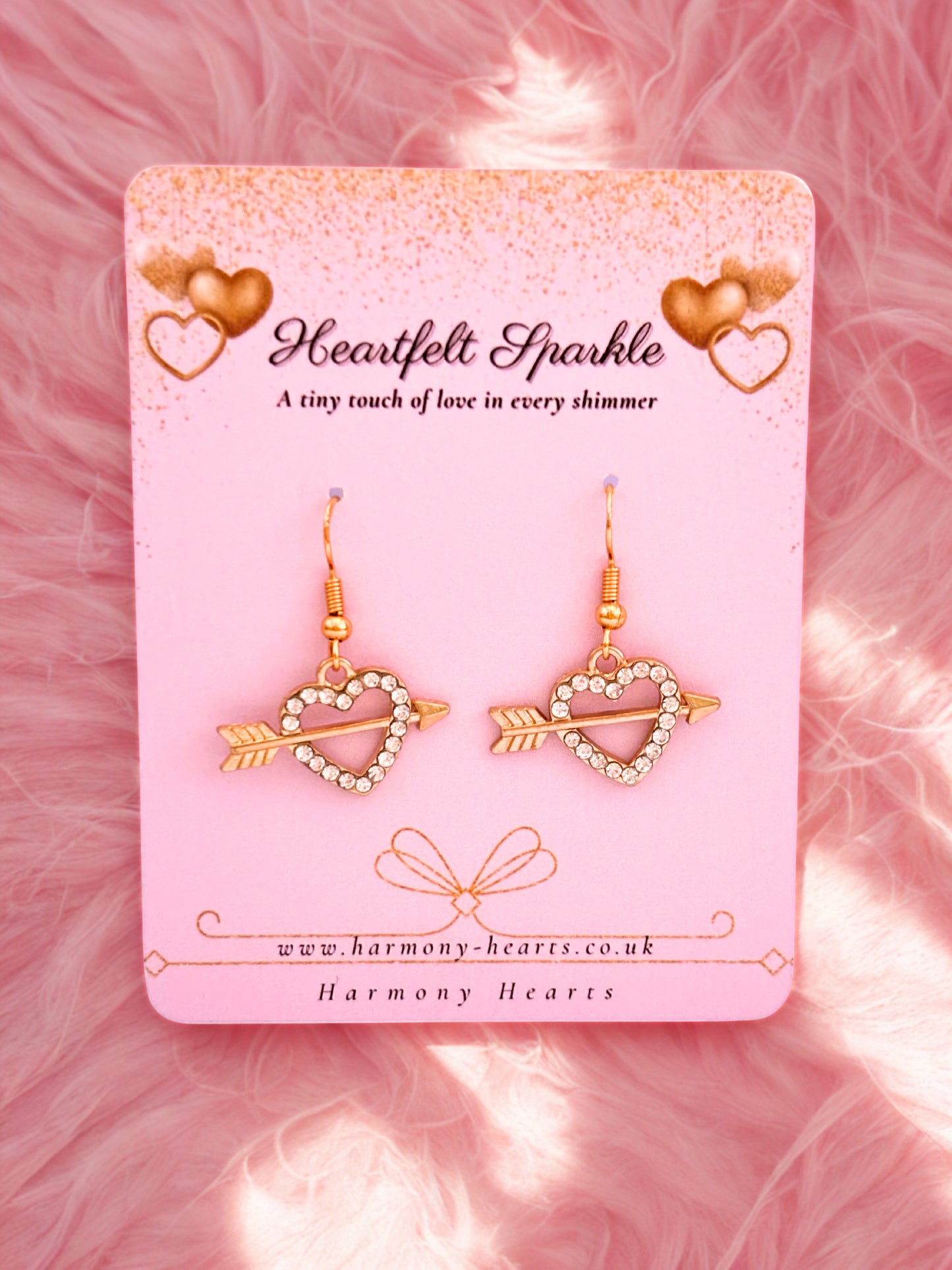 Heart-shaped earrings on a pink card with 'Heartfelt Sparkle' branding.