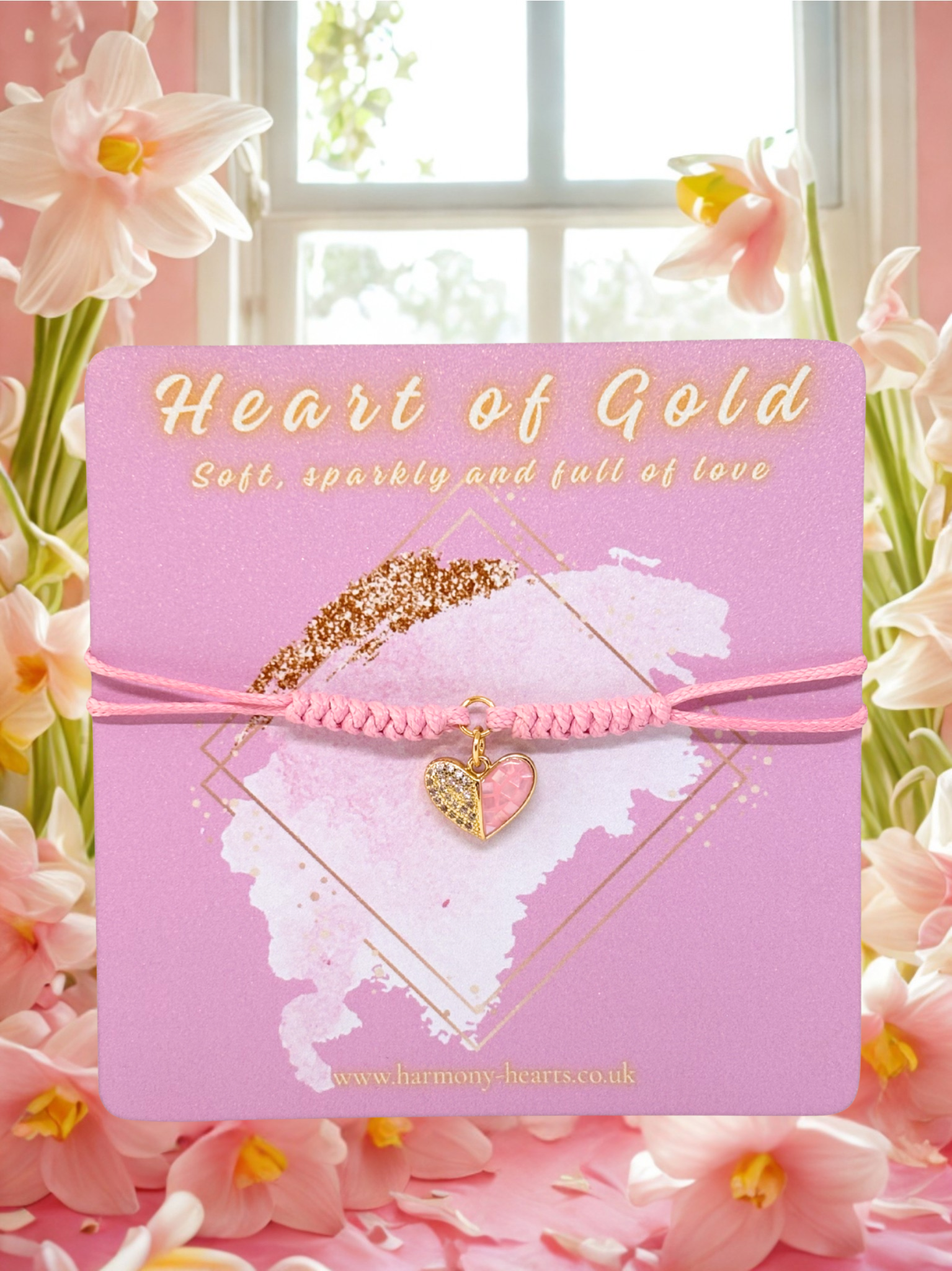 Pink card with a heart-shaped pink and gold charm bracelet on a floral background