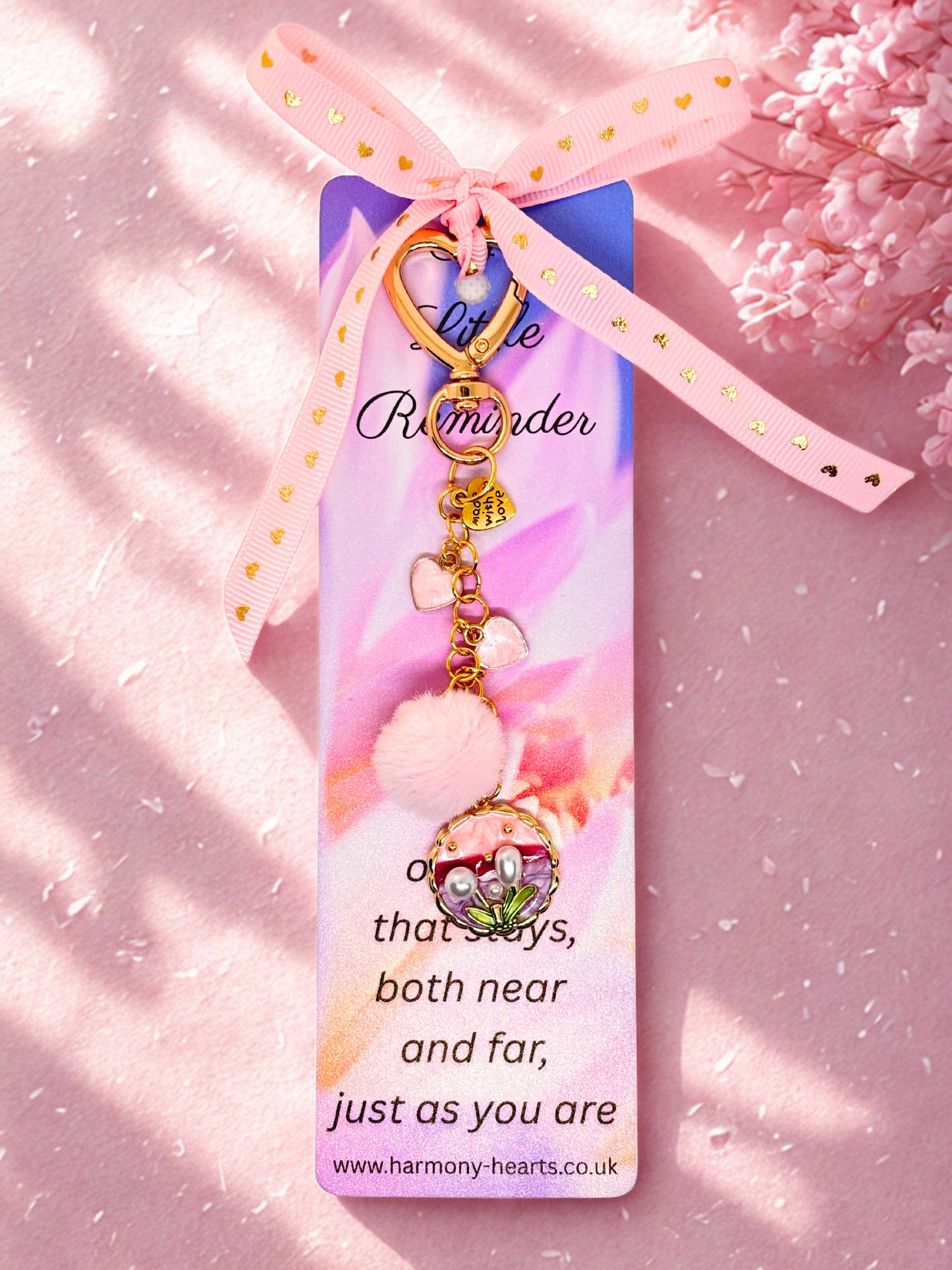 Keychain bag charm with decorative elements on a pink background