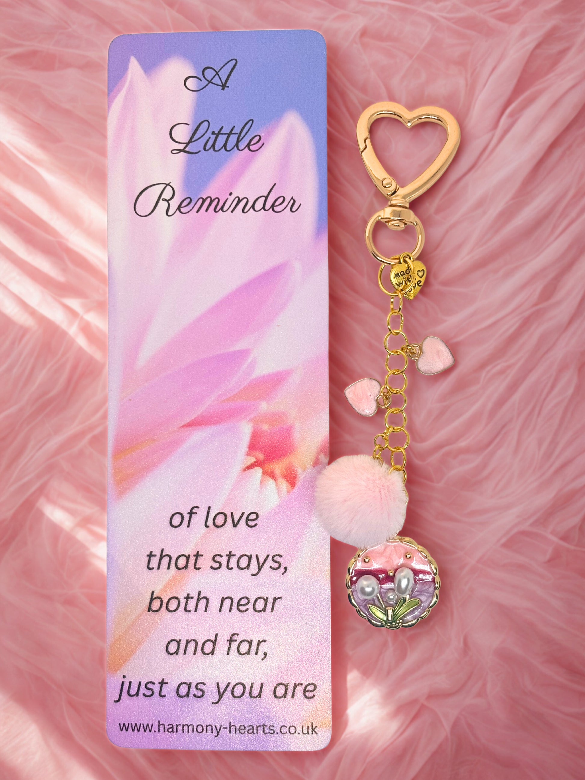 Keychain bag charm with heart design and 'A Little Reminder' card on a pink floral background