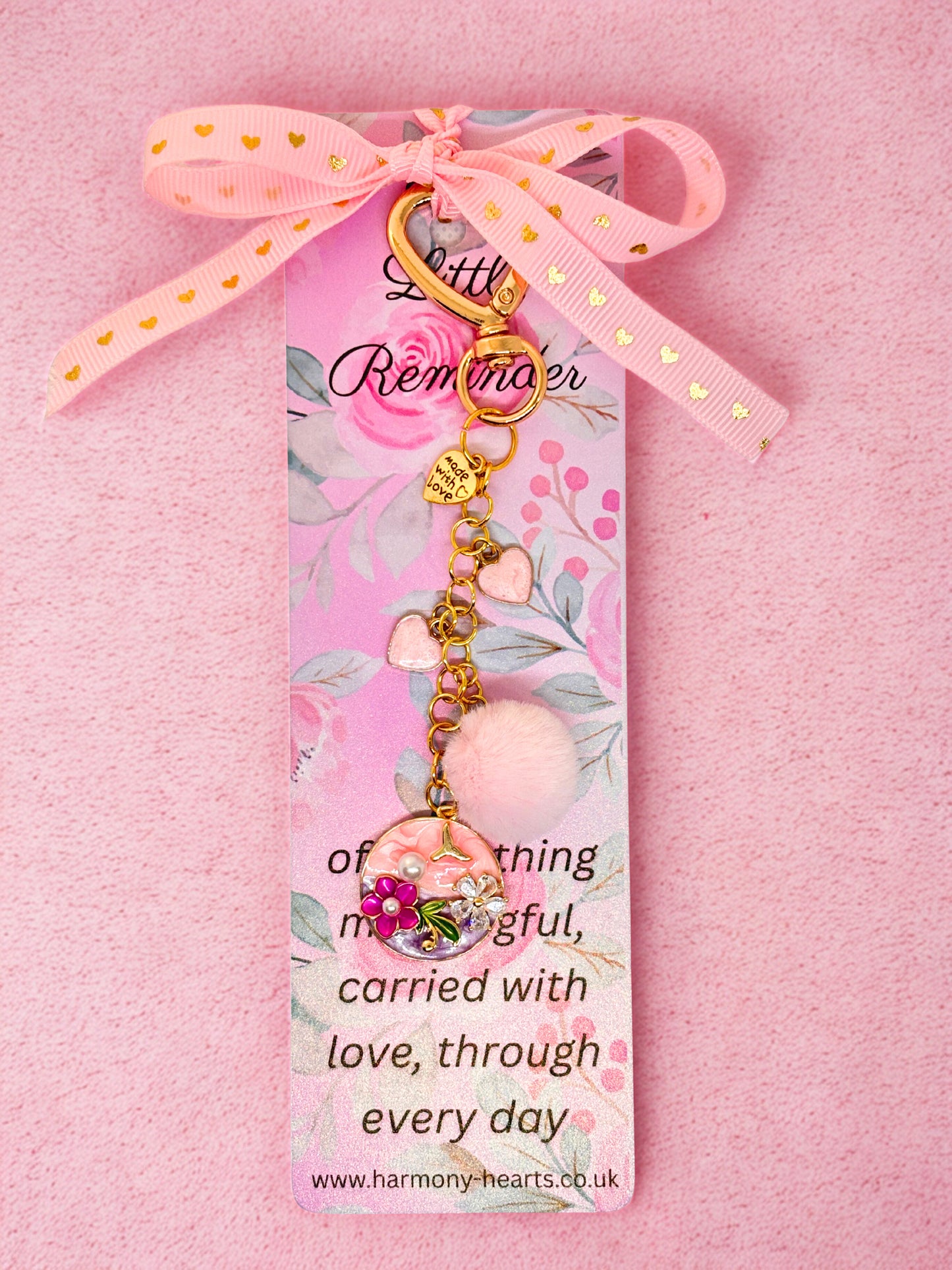 Decorative bag charm with pink ribbon and charm on a pink background