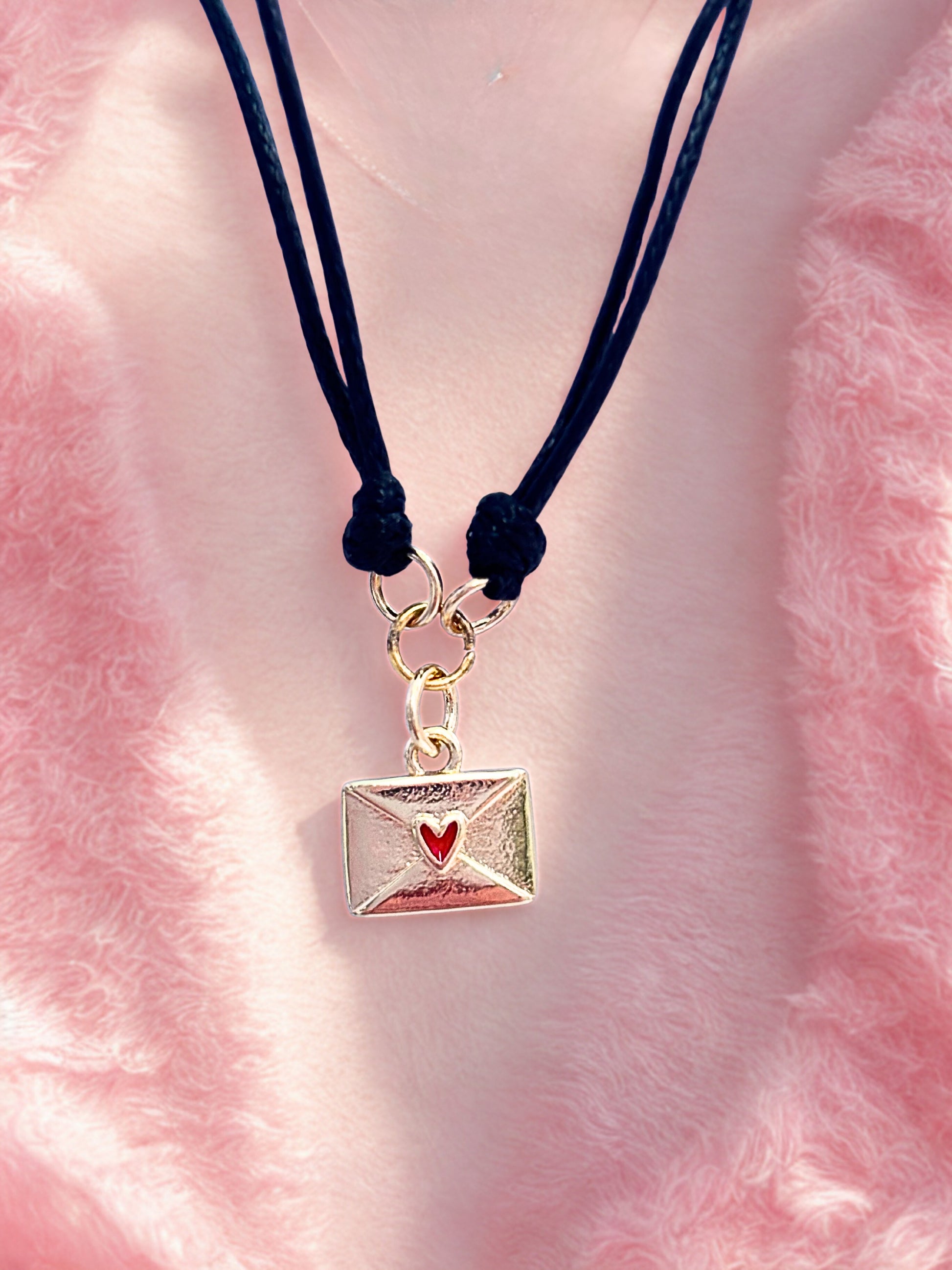 Bracelet with a gold envelope charm on a pink fluffy background