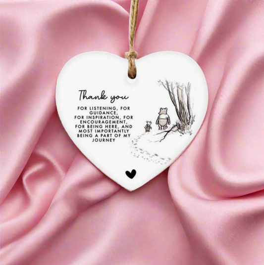 Heart-shaped ceramic plaque with engraved text and illustrations on a pink fabric background