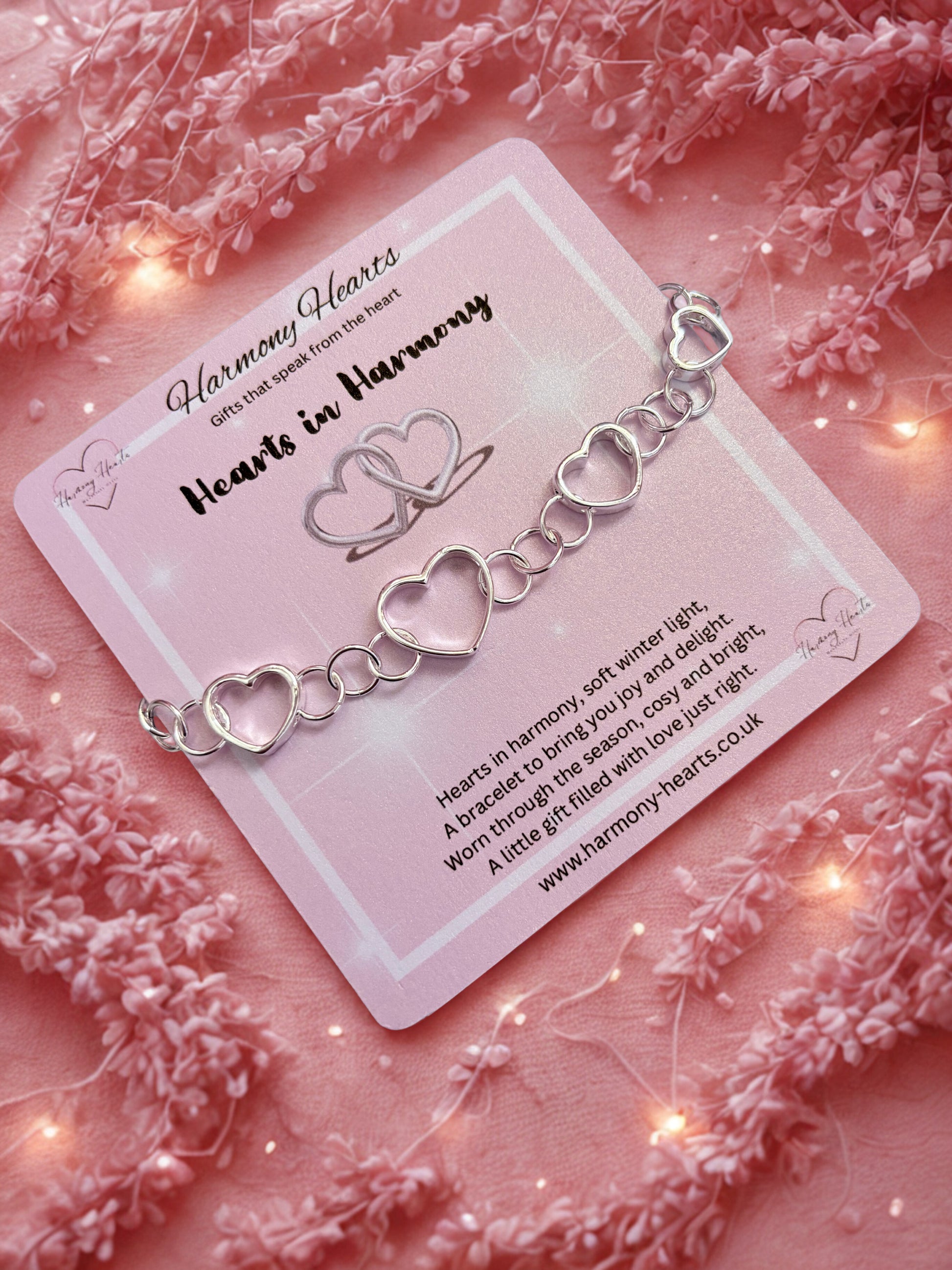 Silver heart-shaped bracelet on a pink card with decorative elements