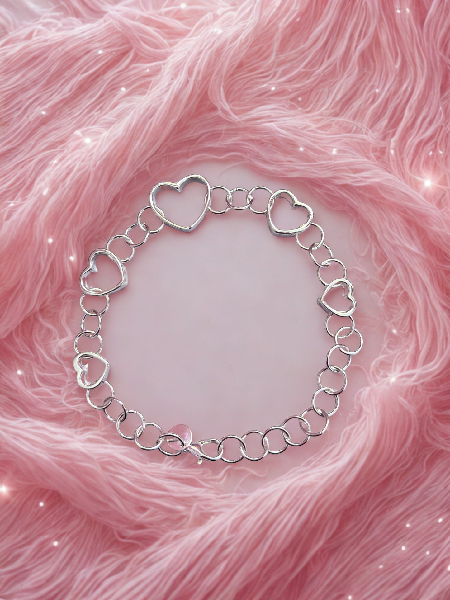 Silver heart-shaped bracelet on a pink textured background