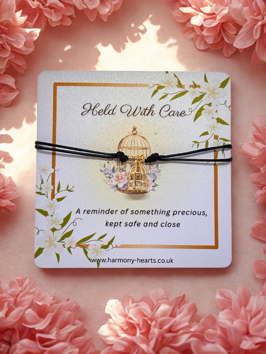 Bird cage charm bracelet on a branded Harmony Hearts card on a pink floral background