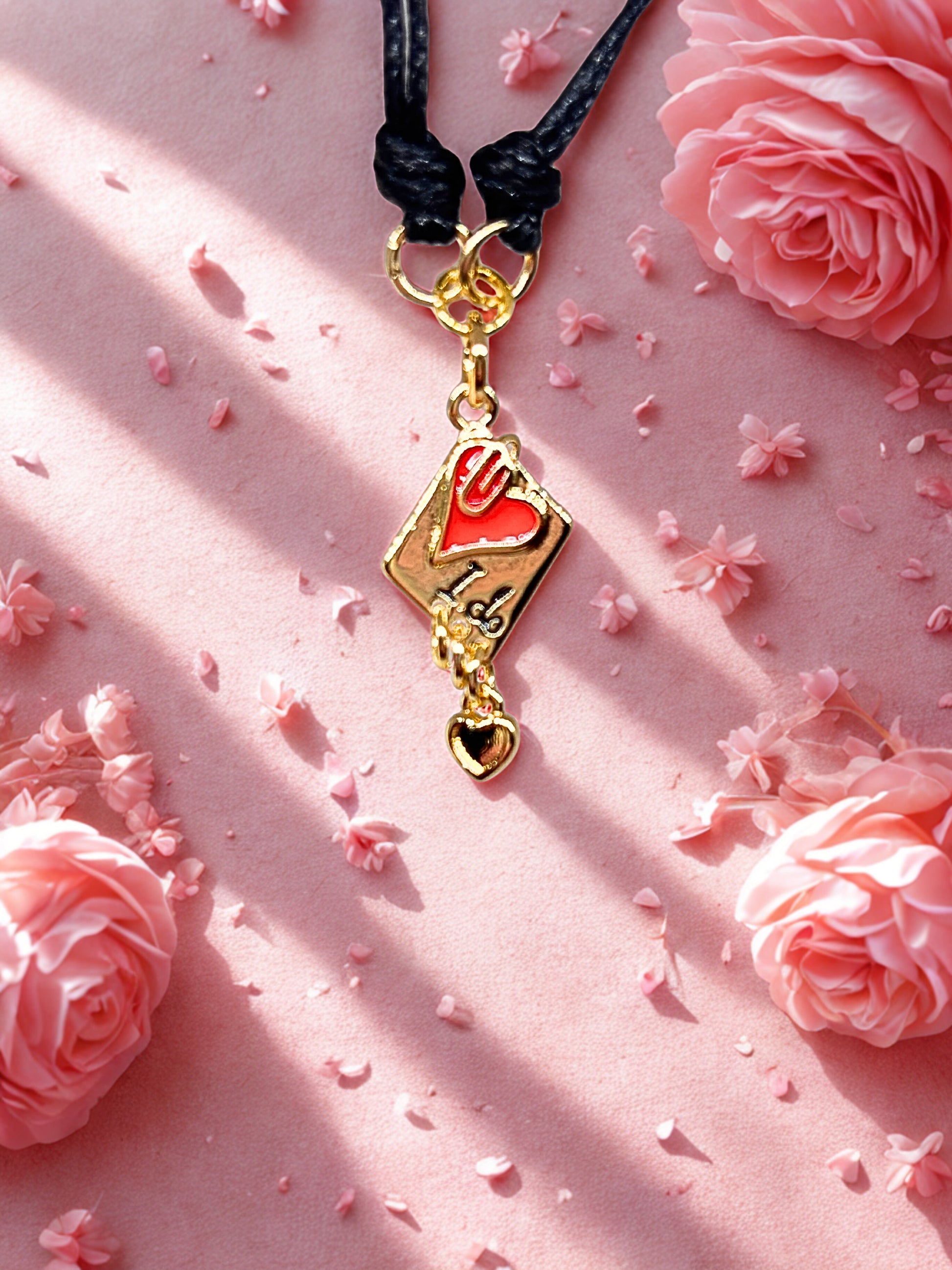 Gold charm on a black cord with pink floral background