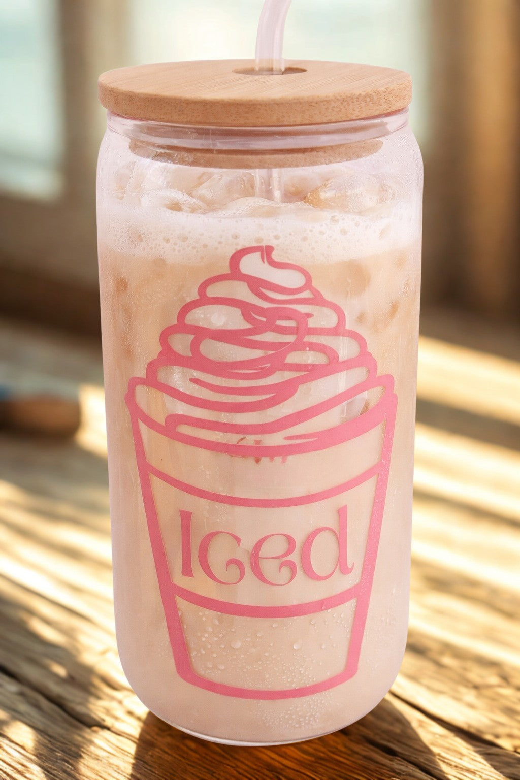 Glass tumbler with a wooden lid and pink 'Iced' design on a wooden surface.