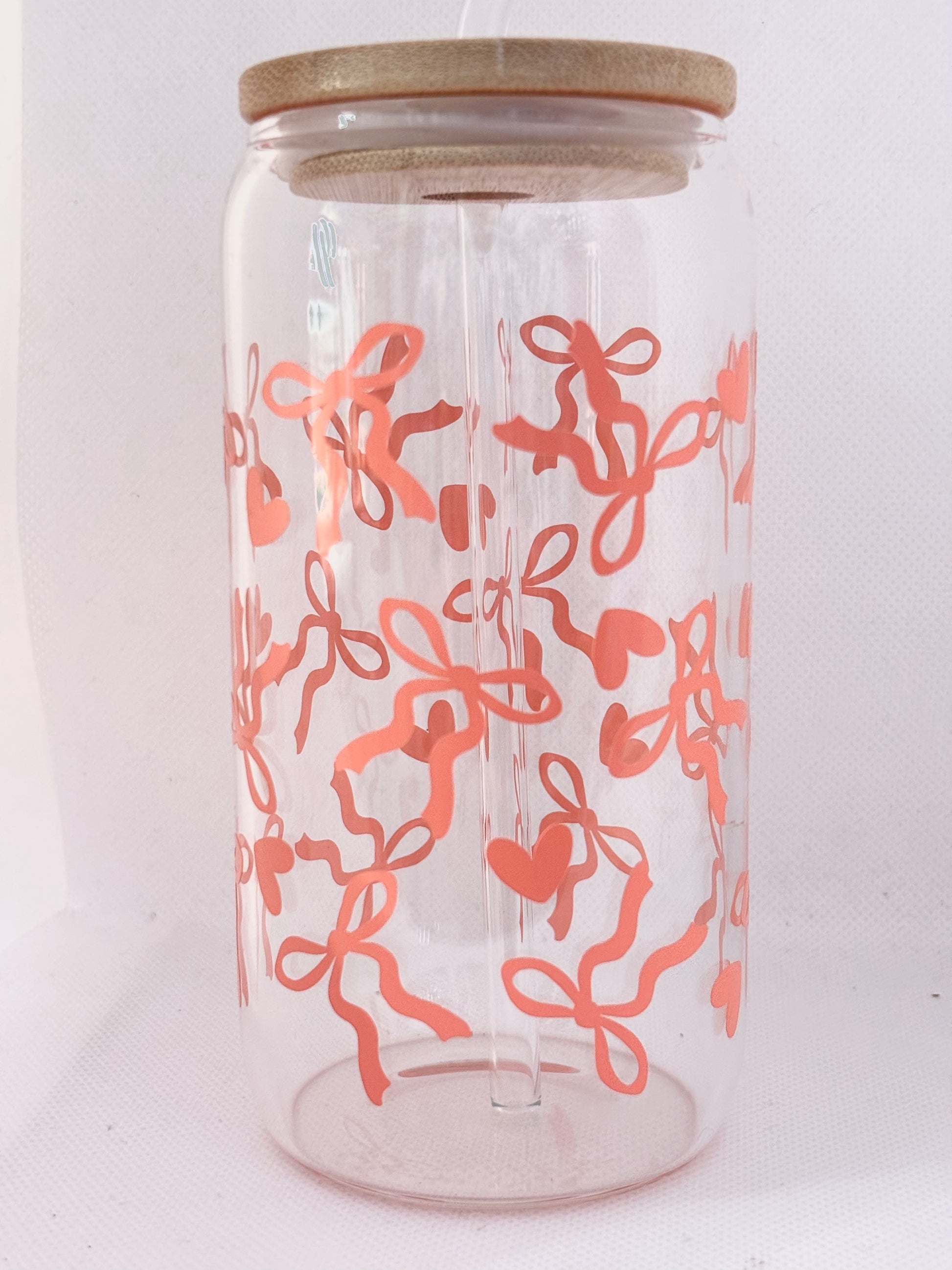 Clear glass  with coral pink bows  and hearts pattern and wooden lid on a white background