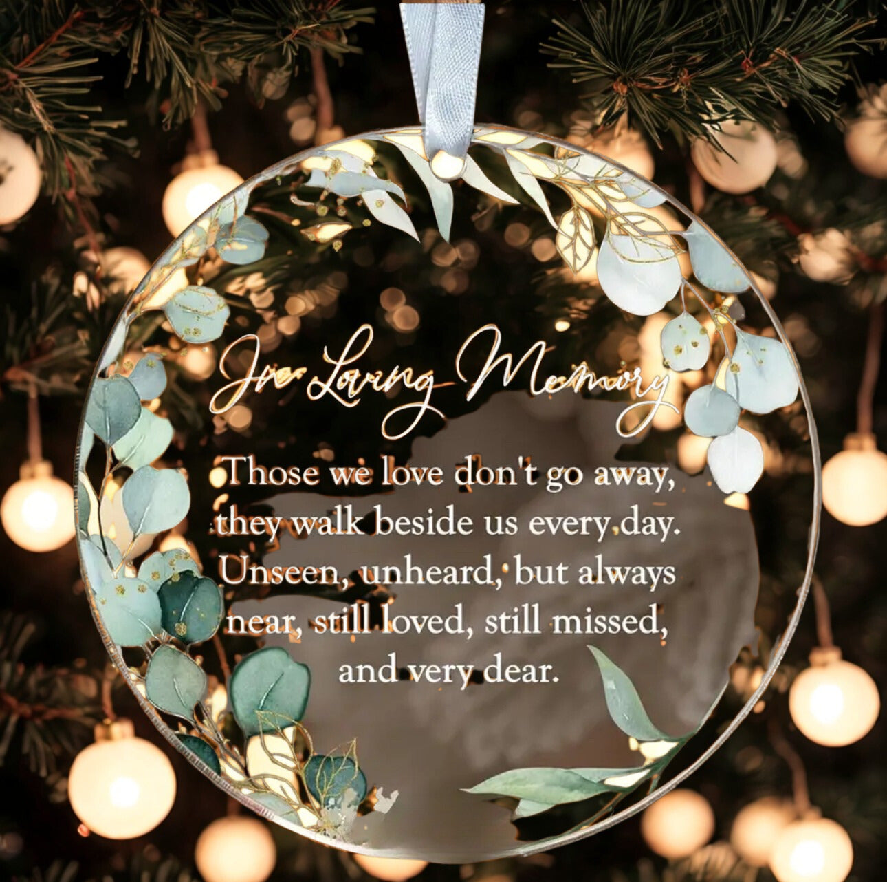 Decorative ornament with a quote about those we love don't go away, hanging on a Christmas tree.