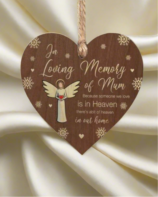 Wooden heart-shaped plaque with an angel illustration and text on a white fabric background