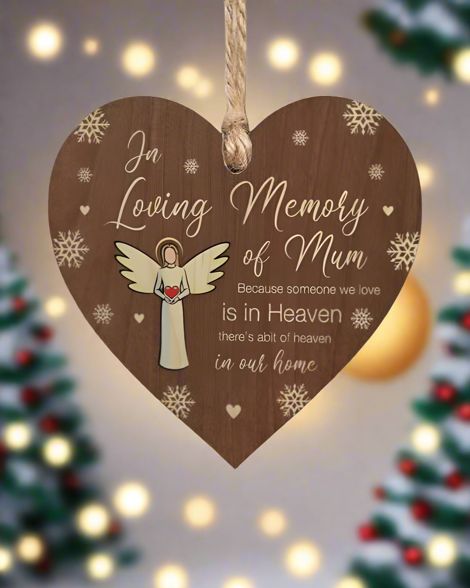 Heart-shaped wooden plaque with angel illustration and text in a festive setting