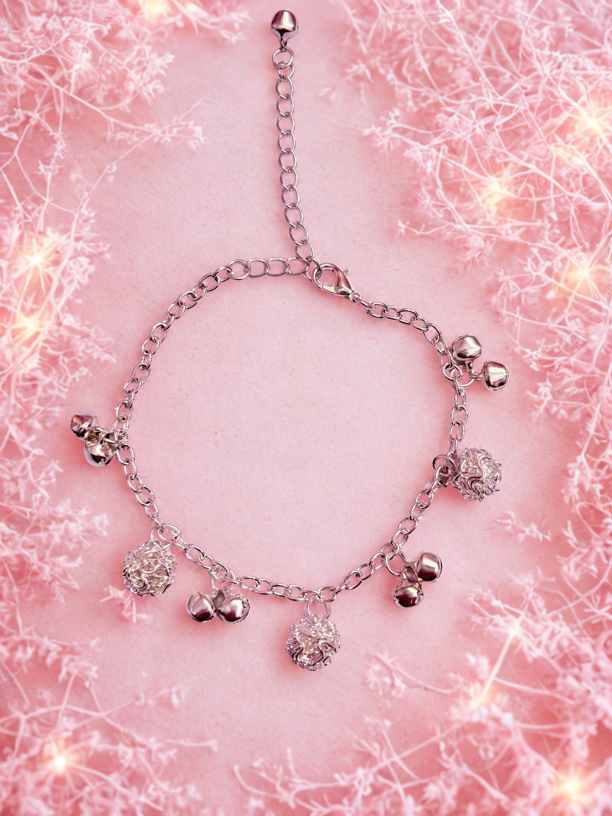 Silver bracelet with charms on a pink textured background