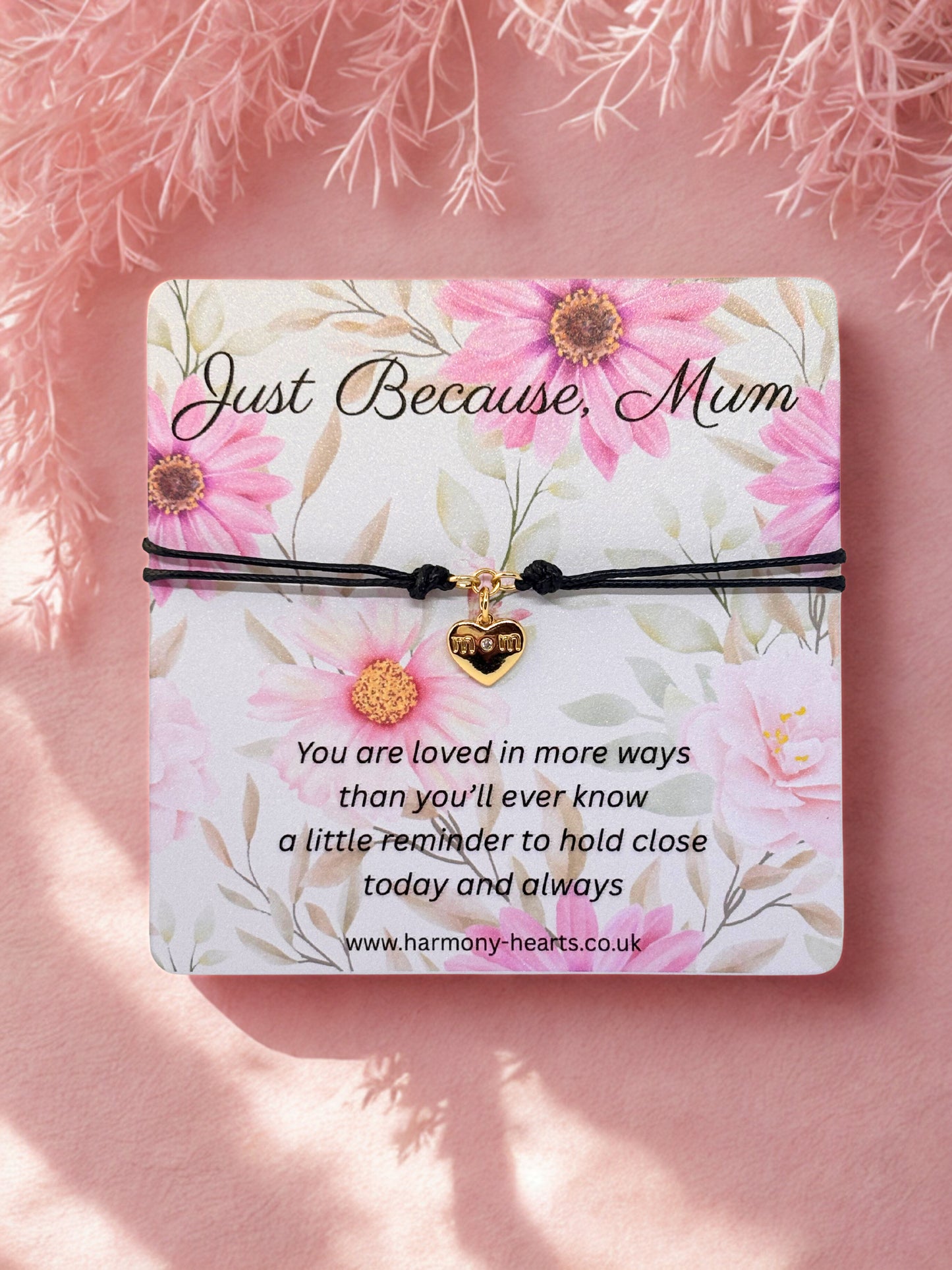 Floral card with heart charm bracelet and message 'Just Because, Mum' on a pink background