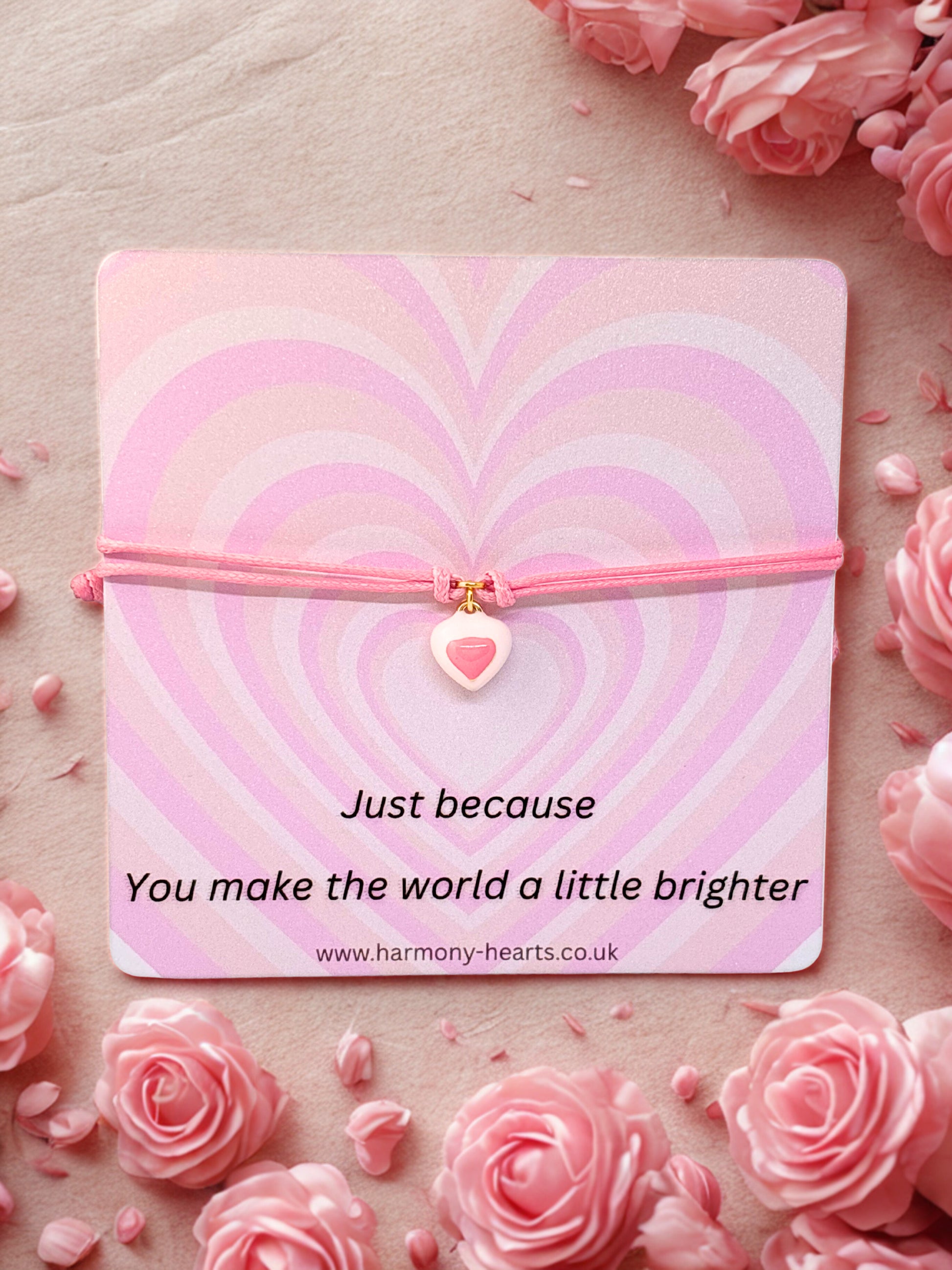 Pink enamel heart charm on a pink cord mounted on a just because card by Harmony Hearts