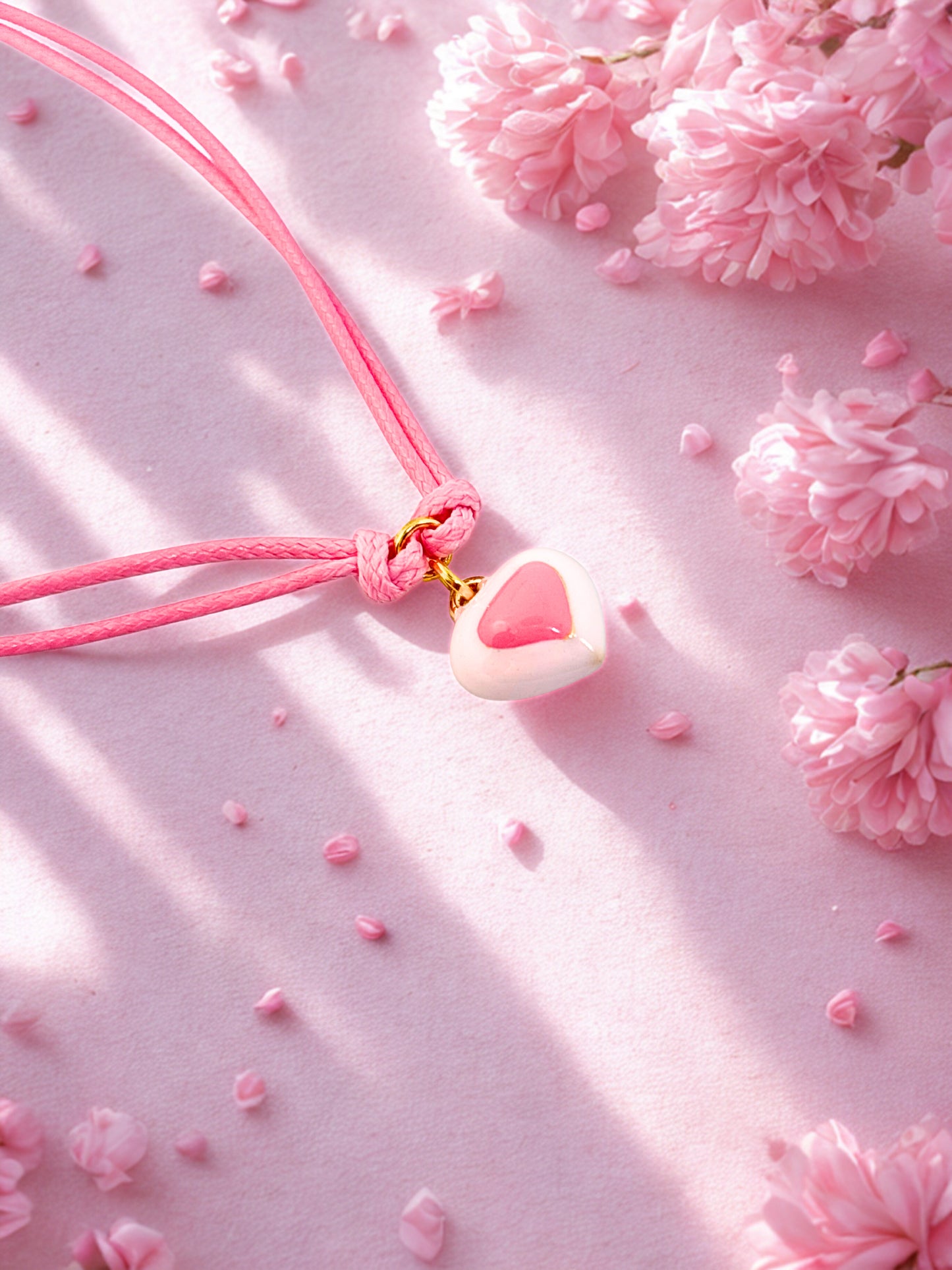 Pink enamel heart charm on a pink cord bracelet