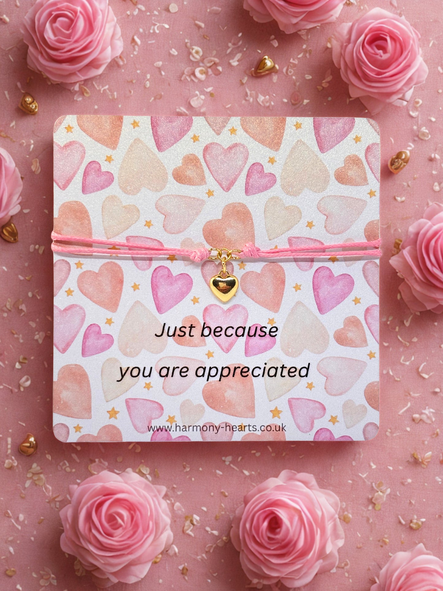 Branded Harmony Hearts card with heart pattern and message 'Just because you are appreciated' with a gold heart charm bracelet on a pink background with roses.