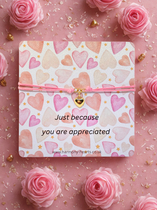 Branded Harmony Hearts card with heart pattern and message 'Just because you are appreciated' with a gold heart charm bracelet on a pink background with roses.