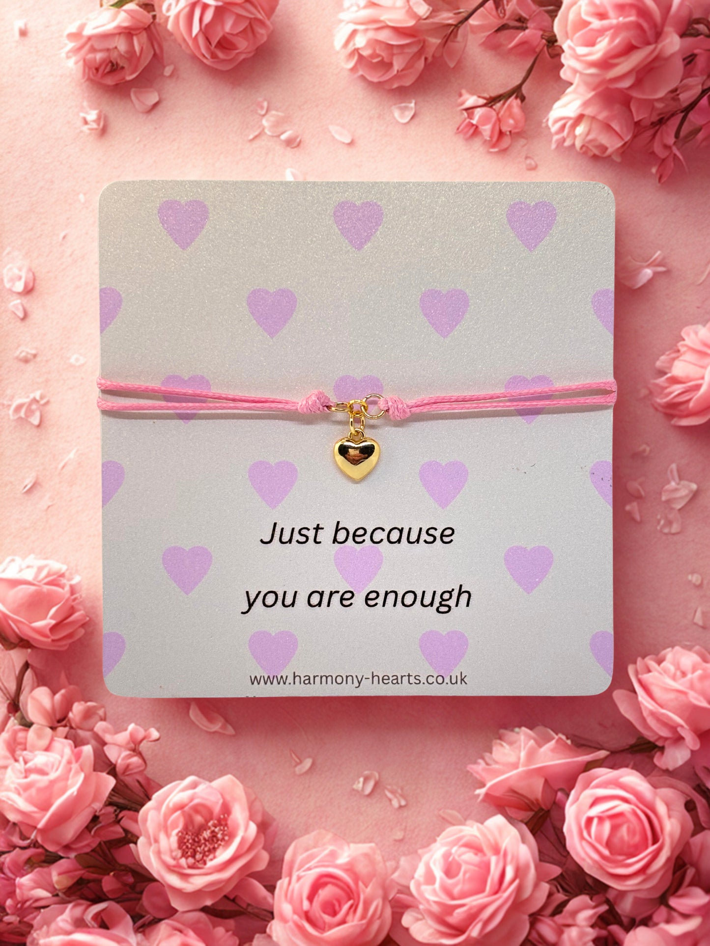 Pink bracelet with heart charm on a Harmony Hearts branded card with 'Just because you are enough' text, surrounded by pink roses.