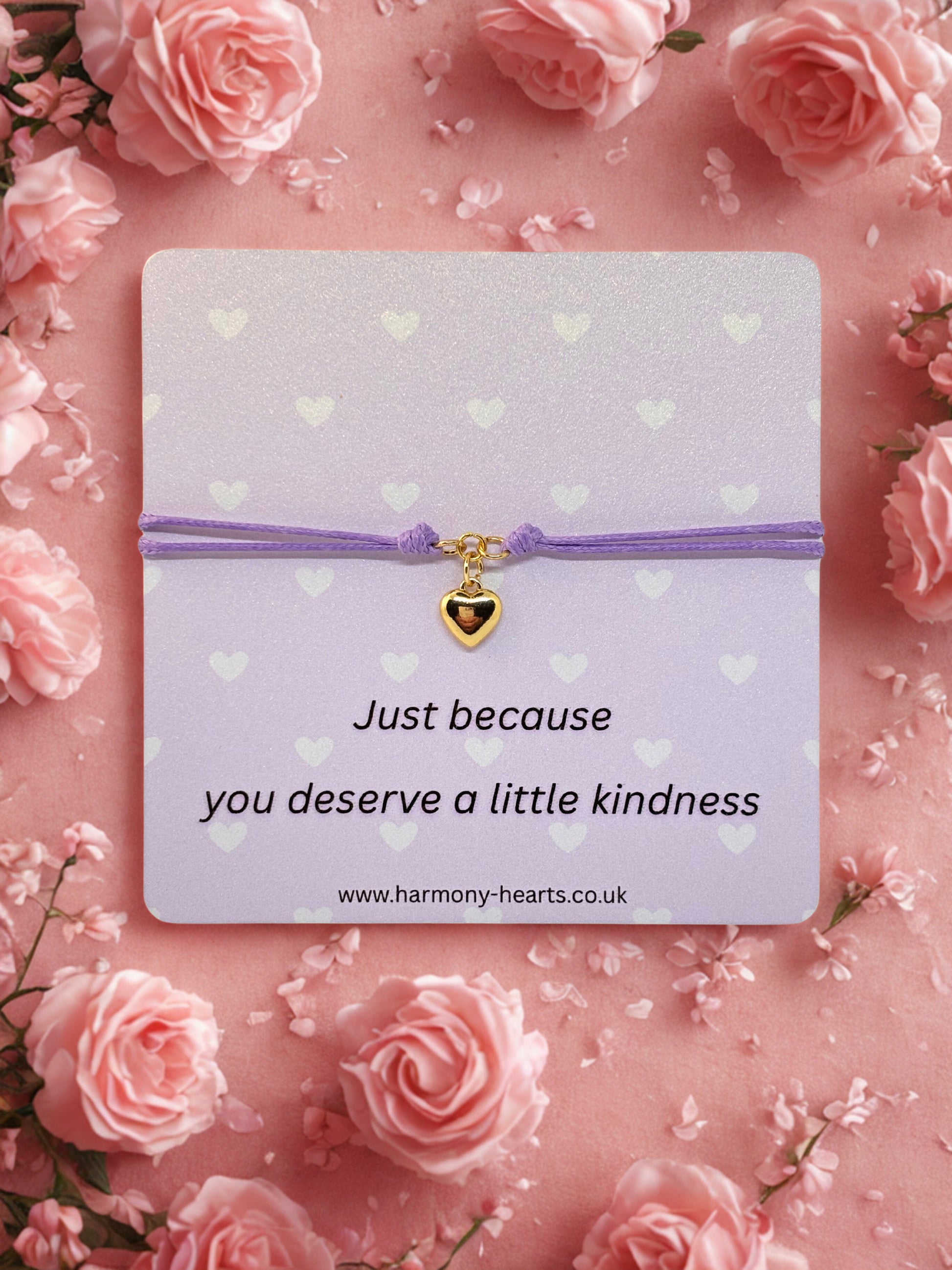Card with a gold heart charm bracelet on a pink floral background with text 'Just because you deserve a little kindness'.