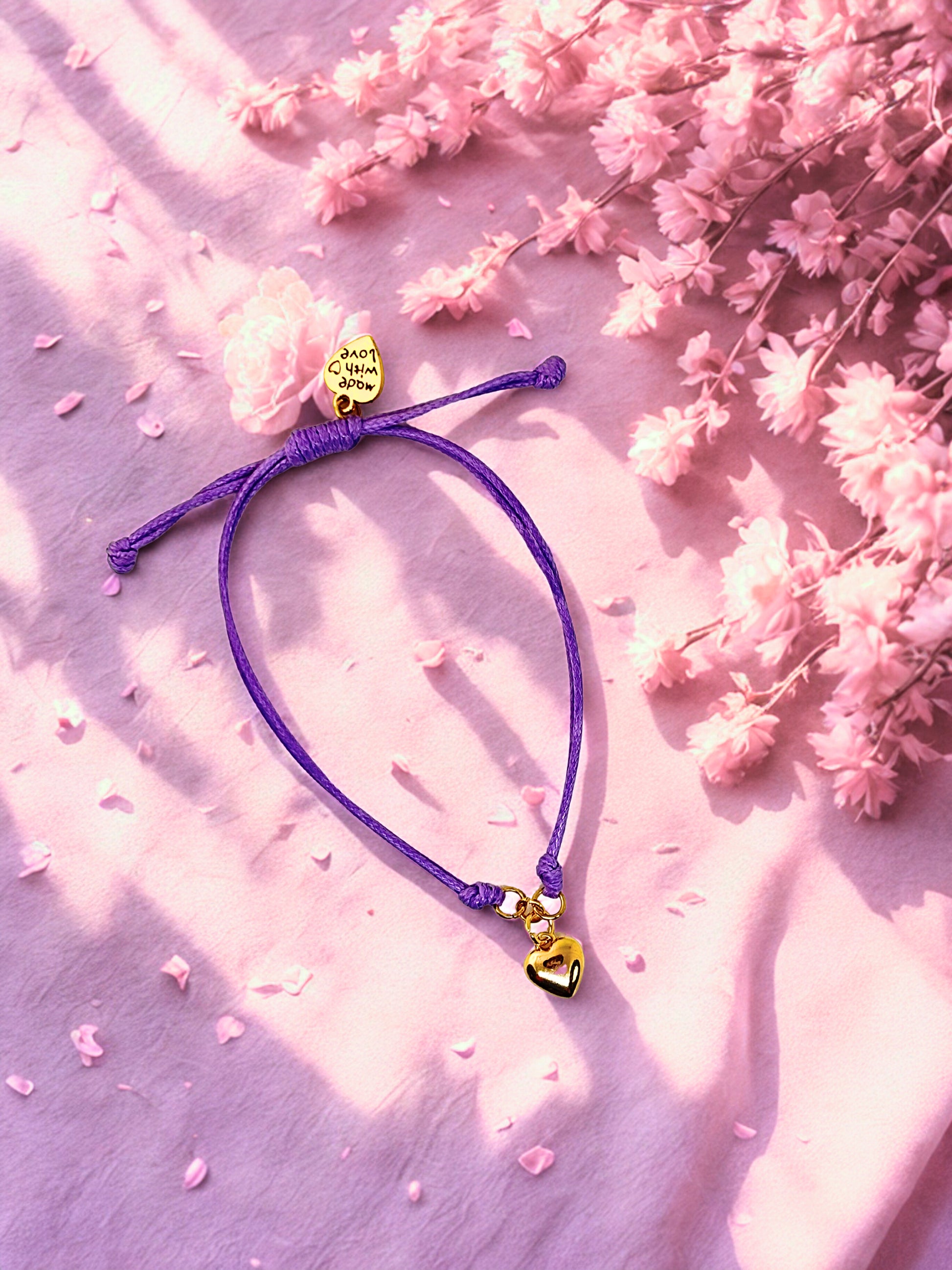Purple bracelet with heart-shaped charms on a pink floral background