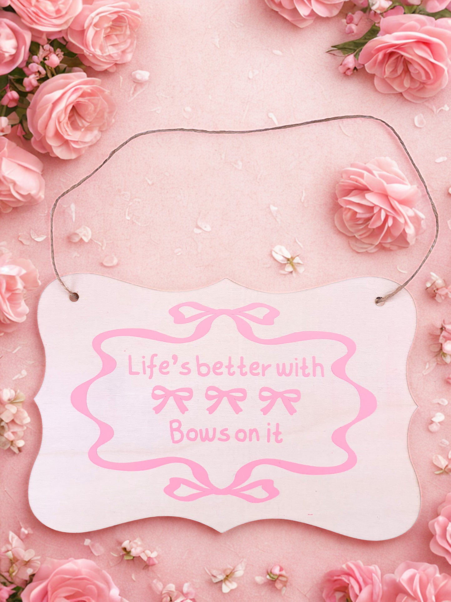 Decorative plaque with 'Life's better with bows on it' text surrounded by pink roses.