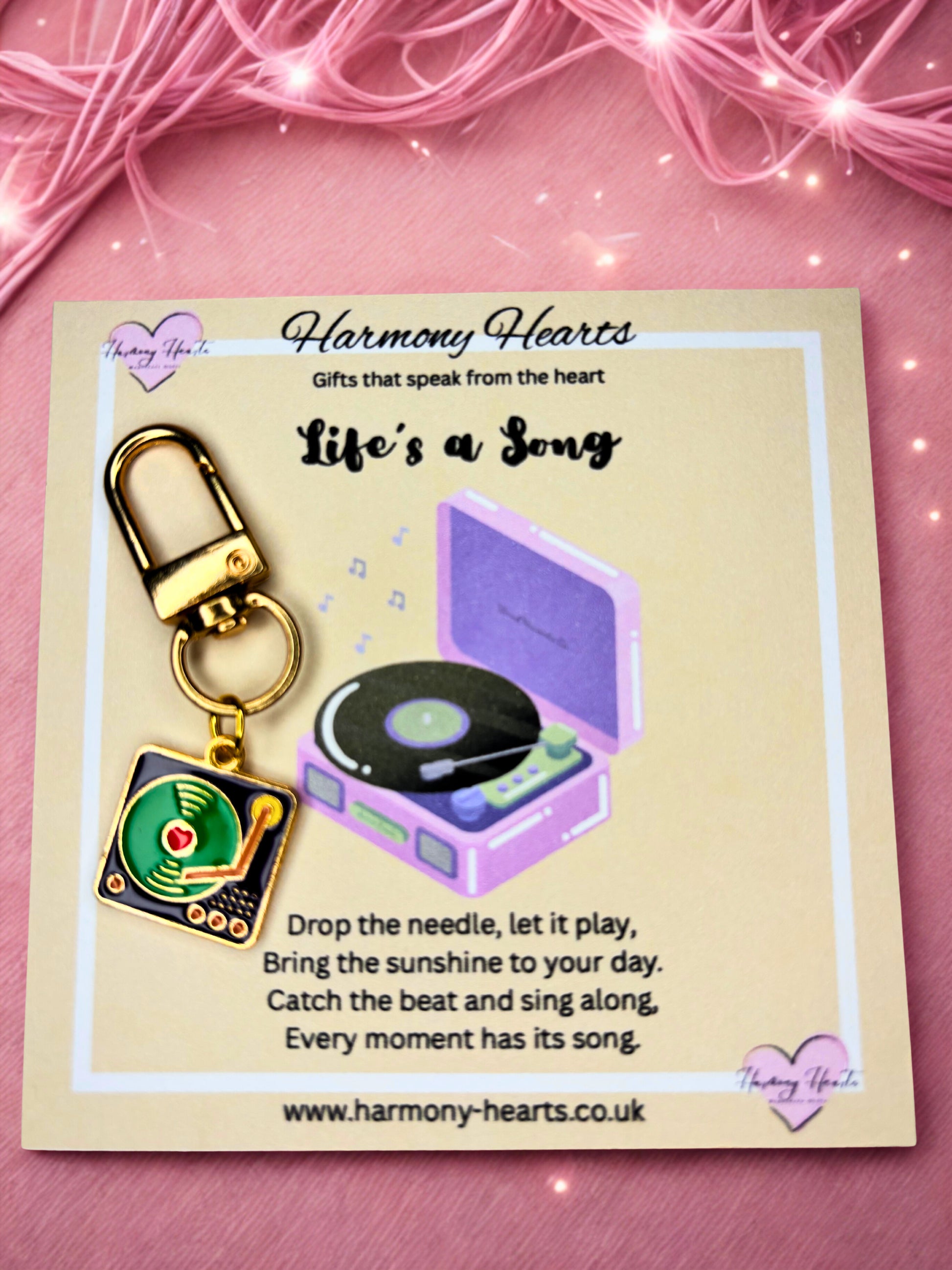 Record player keychain and record on a card with 'Harmony Hearts' branding on a pink background.