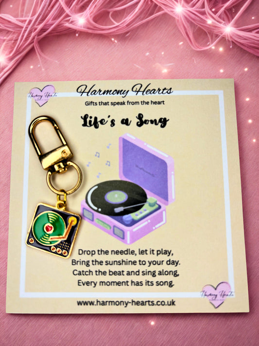 Record player keychain and record on a card with 'Harmony Hearts' branding on a pink background.