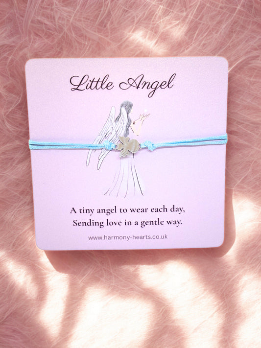 Angel bracelet on a pink card with 'Little Angel' text, displayed on a textured pink surface.