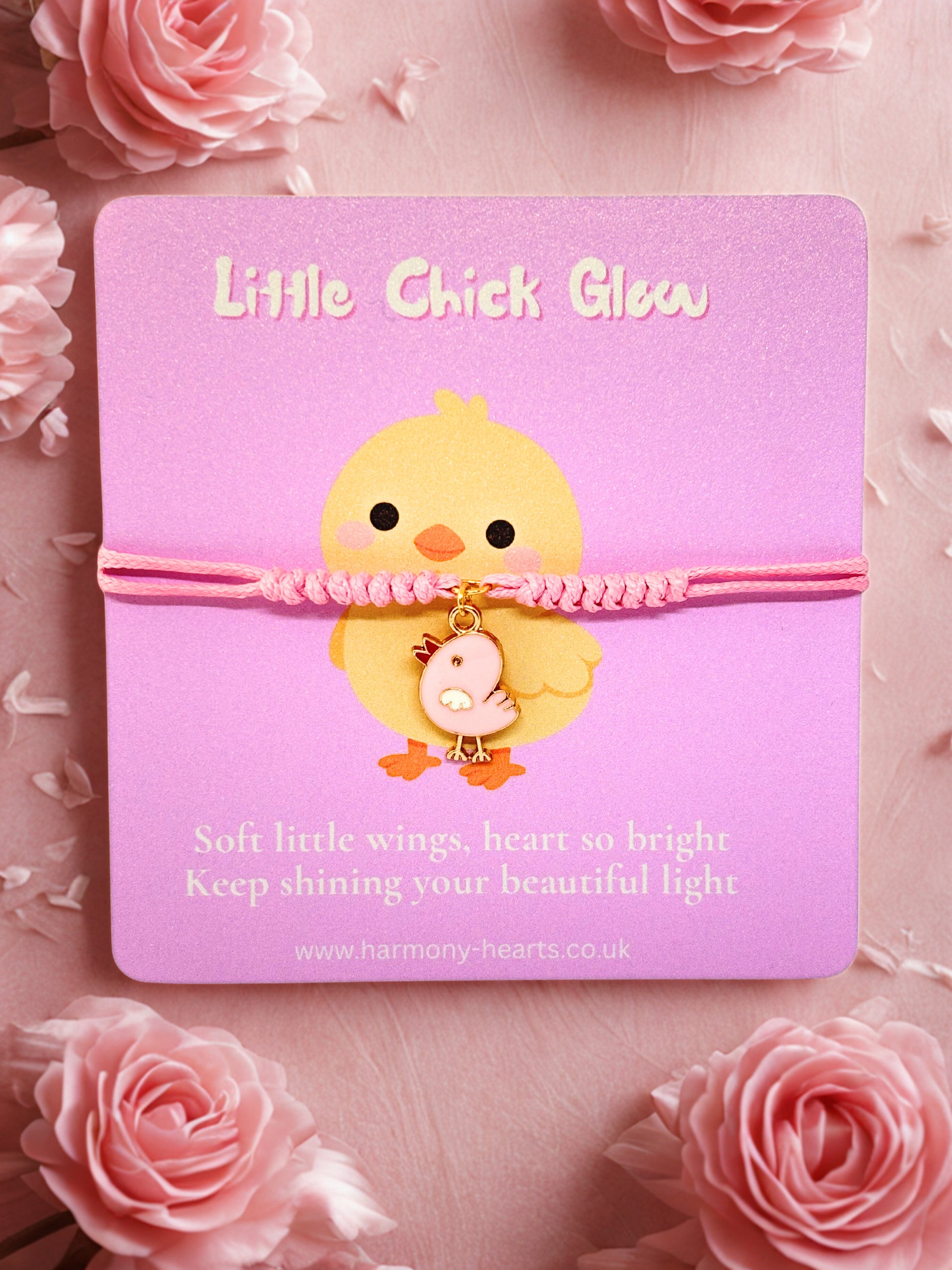 Pink cord bracelet with pink chick charm on a branded Harmony Hearts card with a chick design and 'Little Chick Glow' text, surrounded by pink flowers.