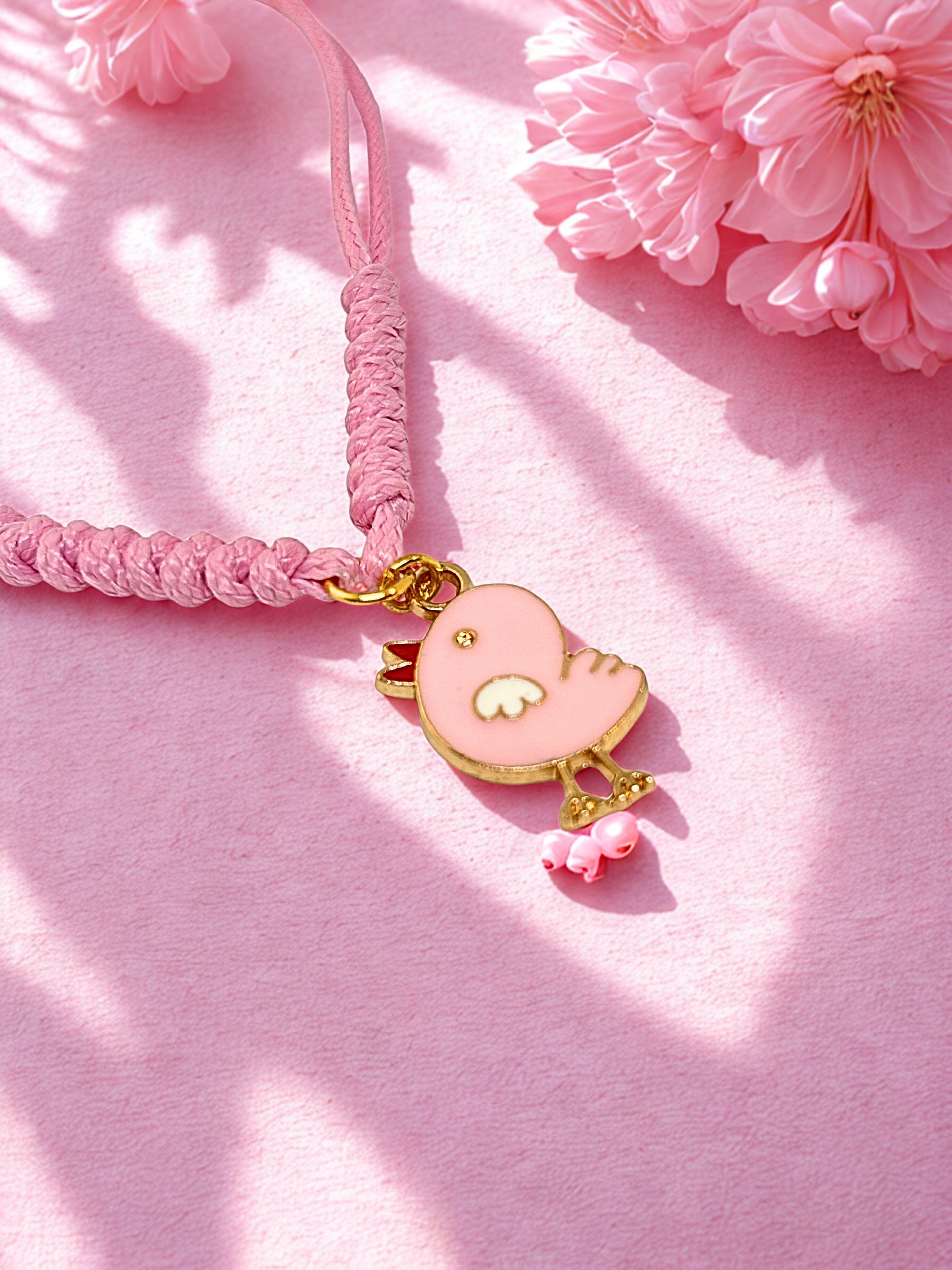 Pink braided bracelet with a pink chick charm on a pink background