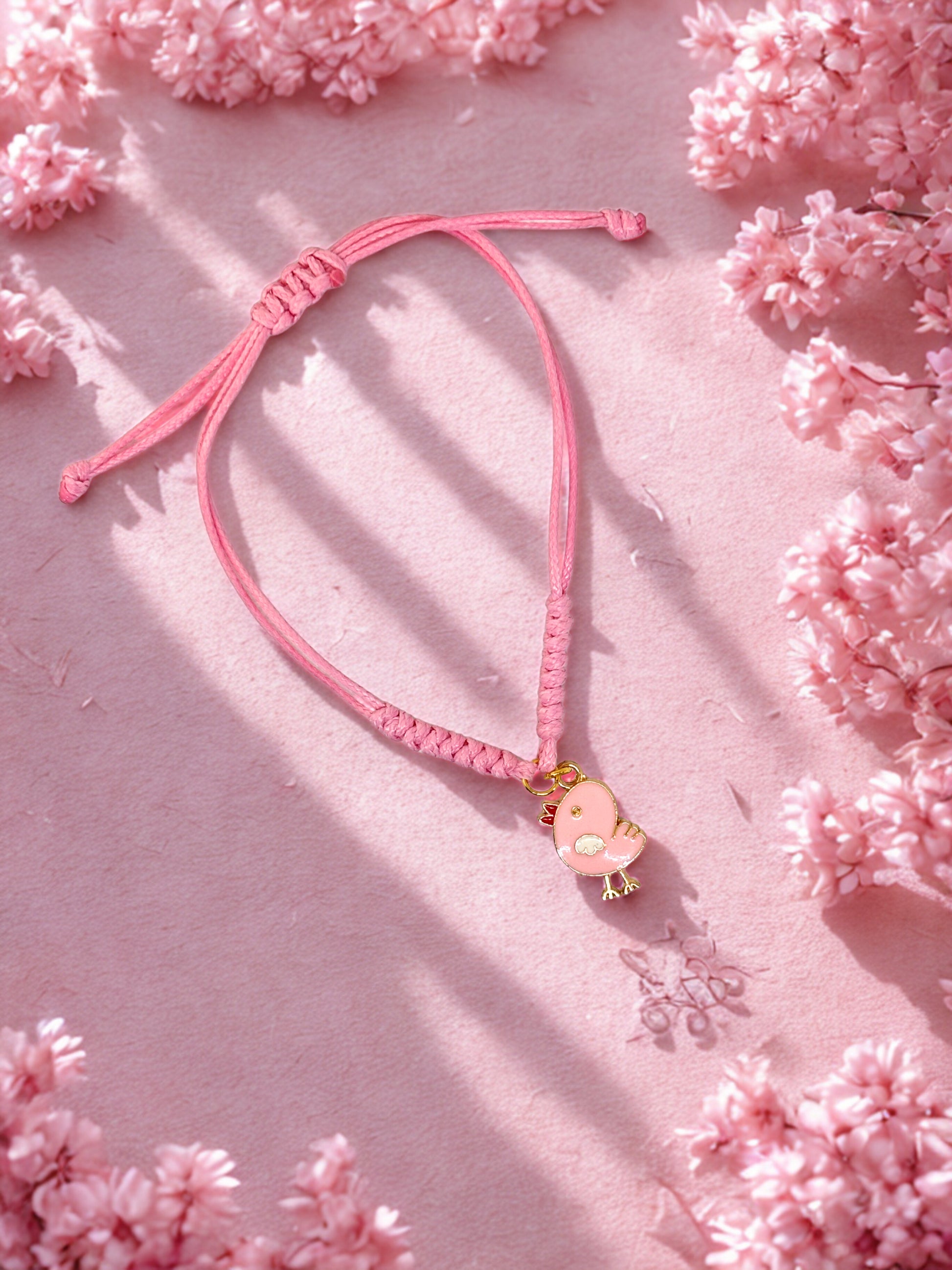 Pink bracelet with a pink chick charm on a pink floral background