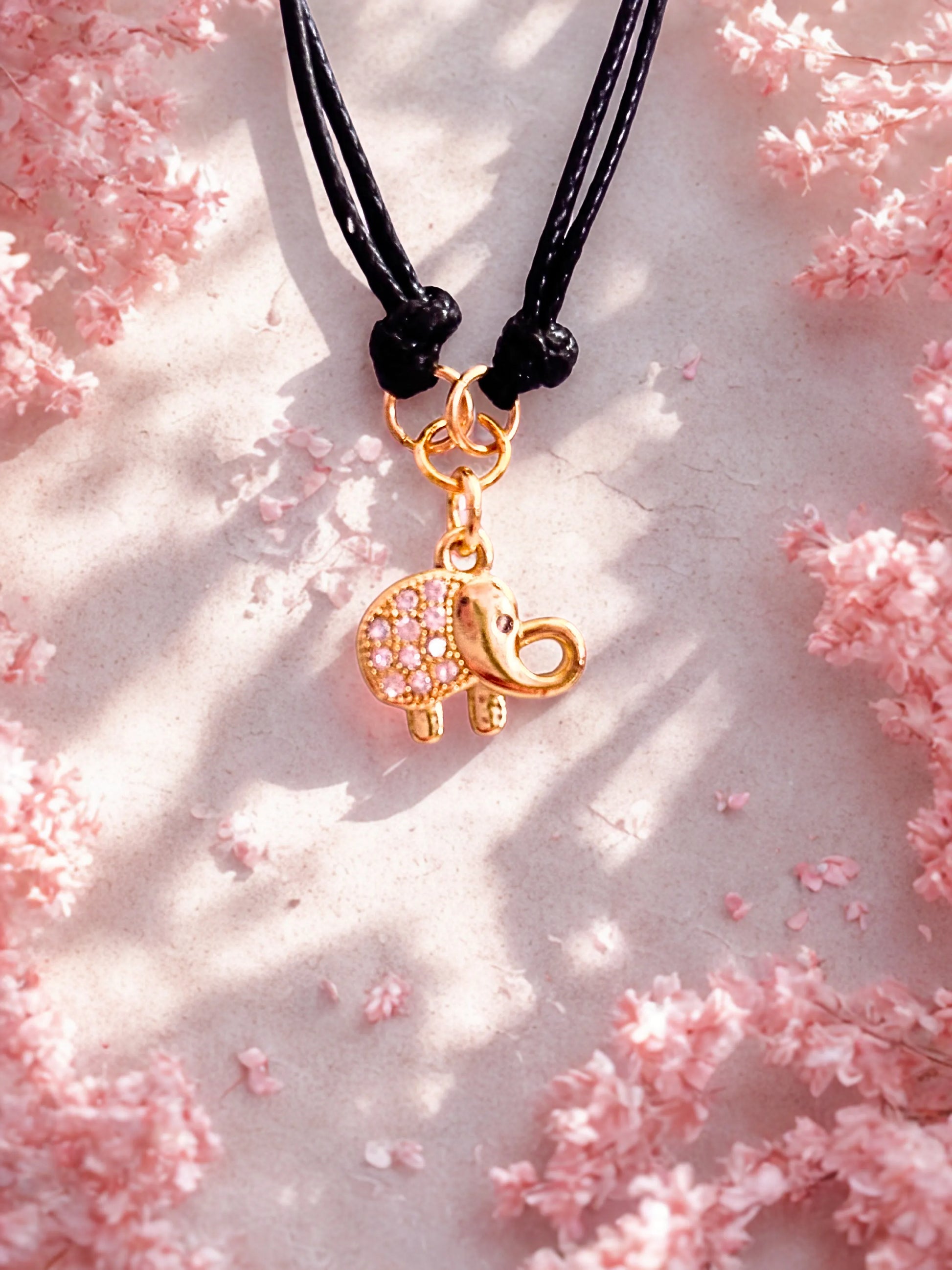 bracelet with a gold elephant charm on a pink floral background