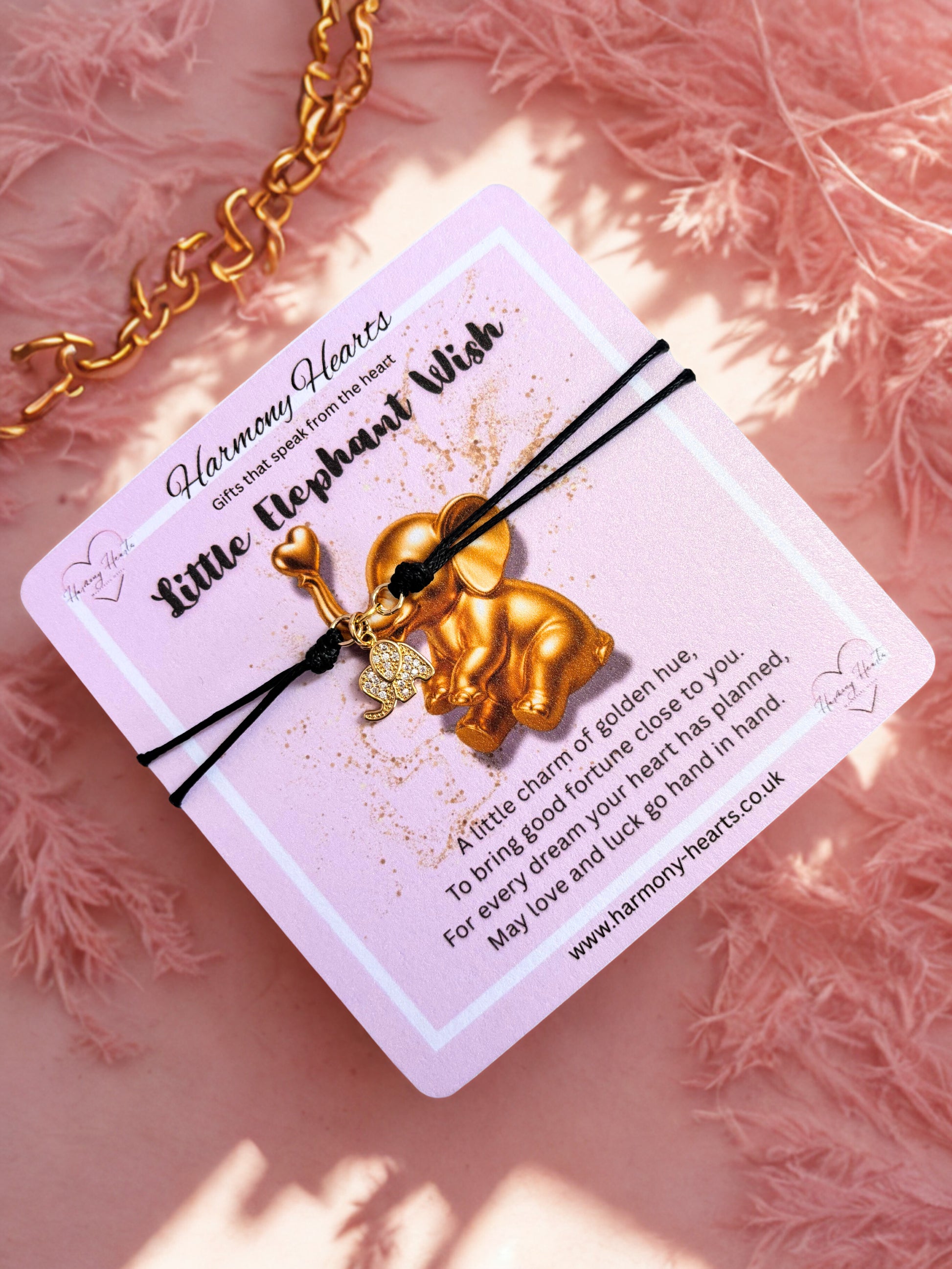 Black cord bracelet with gold elephant charm on a pink poem card