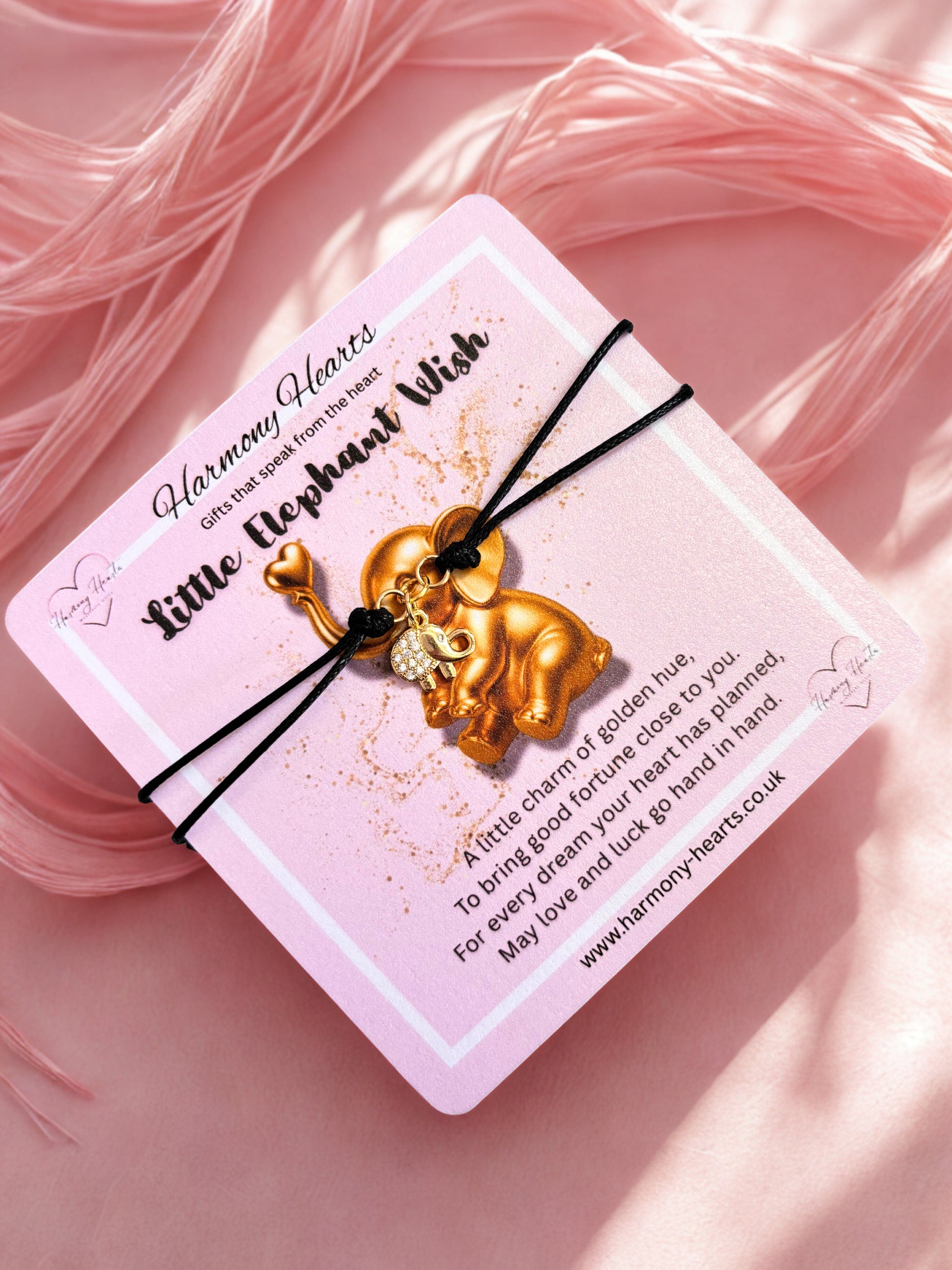 Gold elephant charm bracelet on a pink card with text