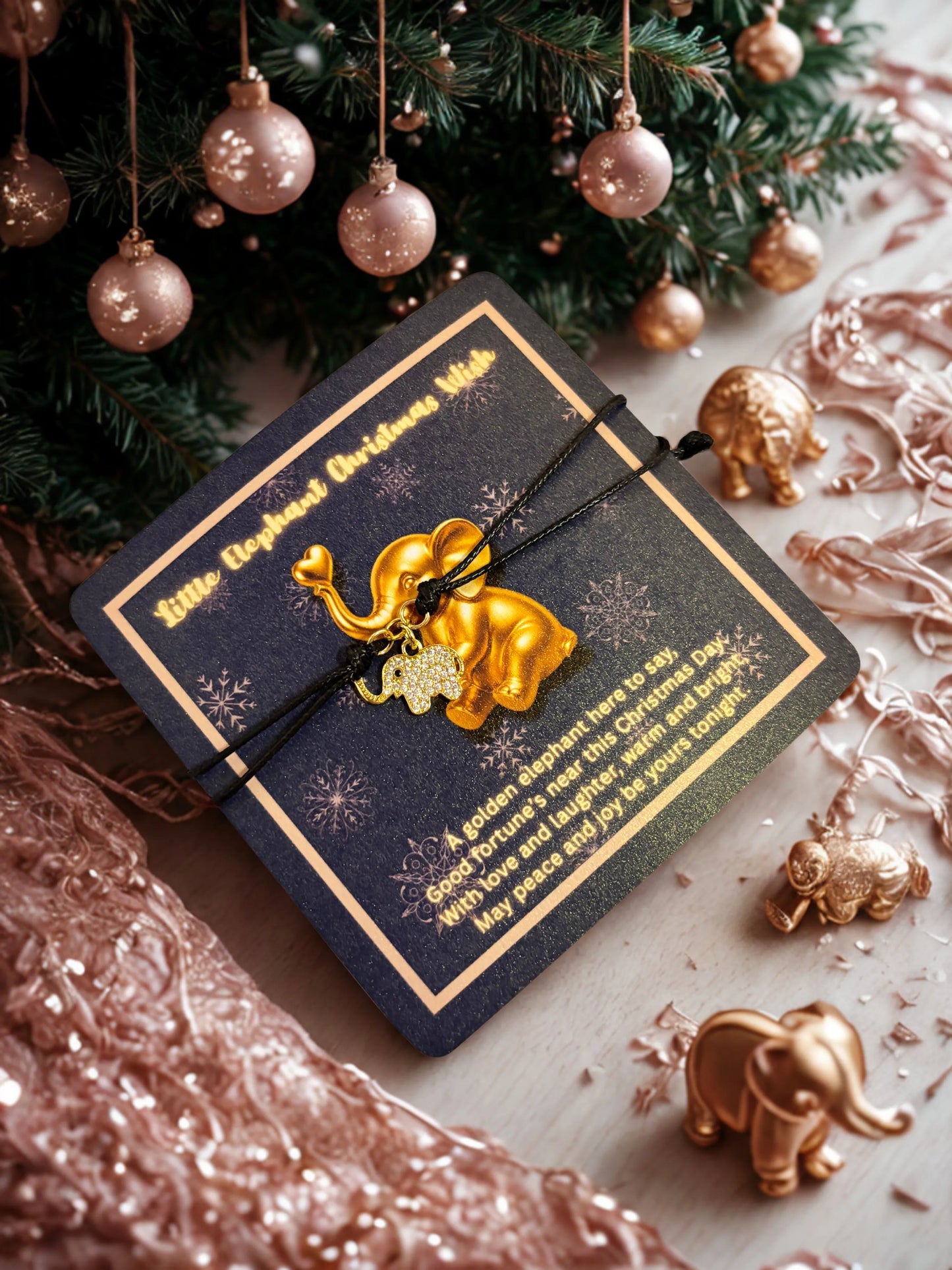 Gold elephant charm bracelet on a decorative card with Christmas tree and ornaments in the background