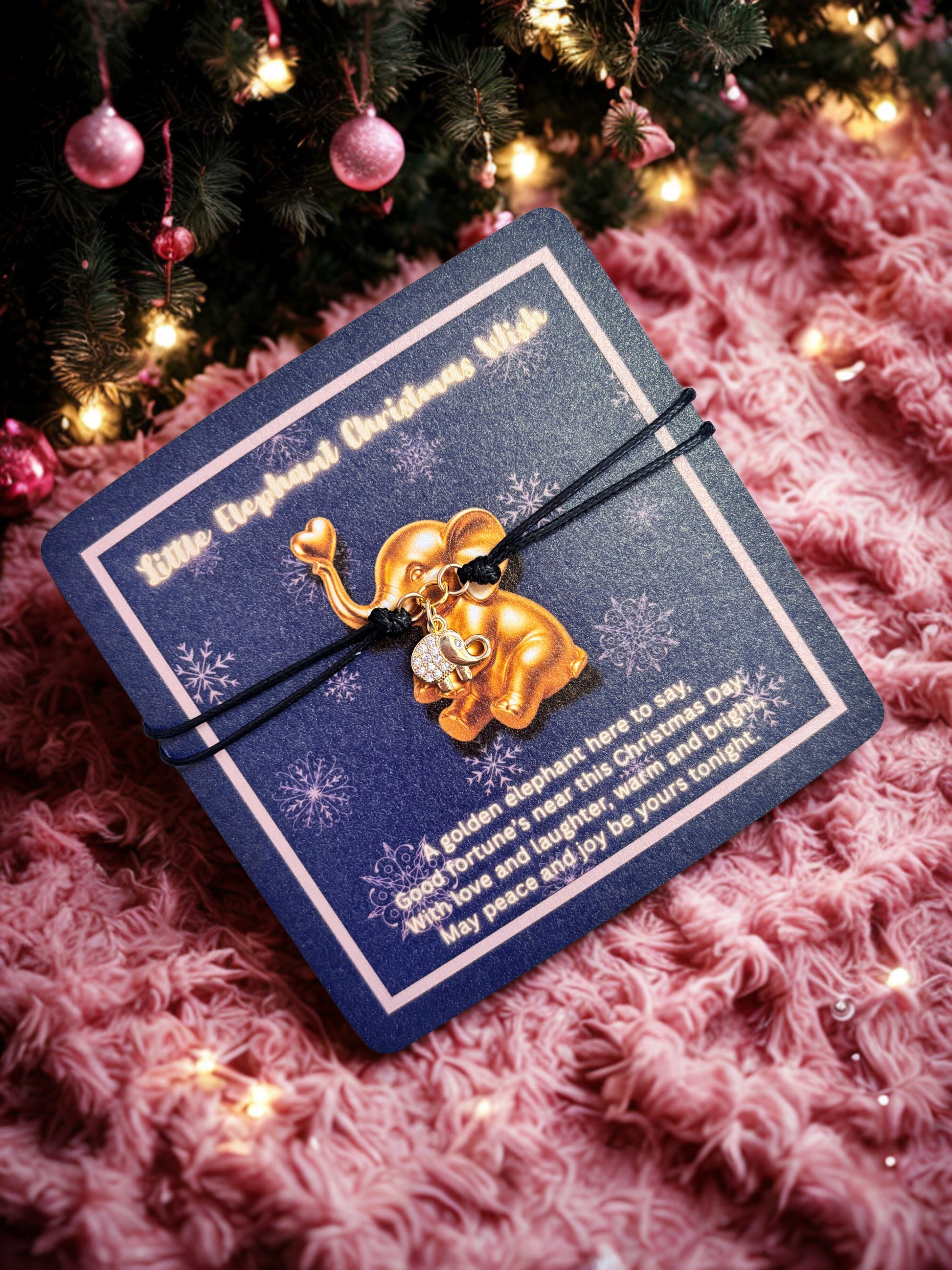 Gold elephant charm bracelet on a blue card with Christmas tree and decorations in the background