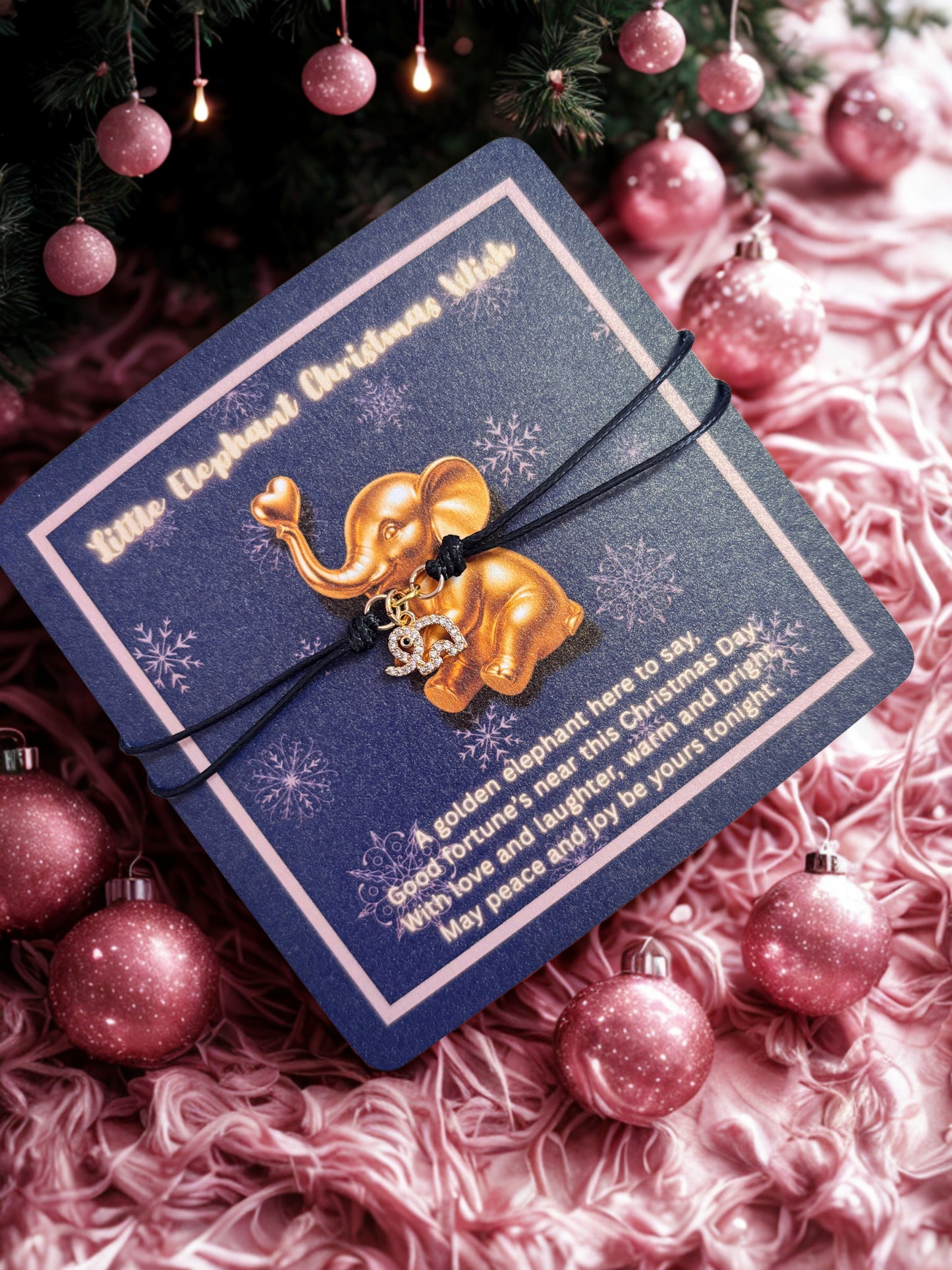 Gold elephant charm bracelet on a blue card with pink Christmas decorations