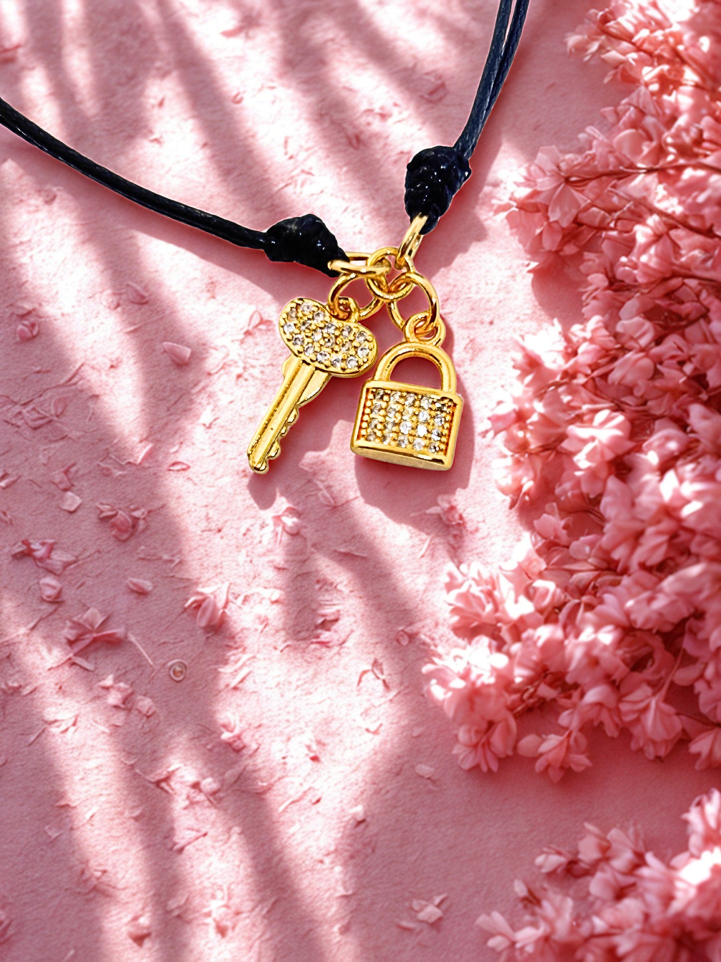 Bracelet with gold key and lock charms on a pink textured background