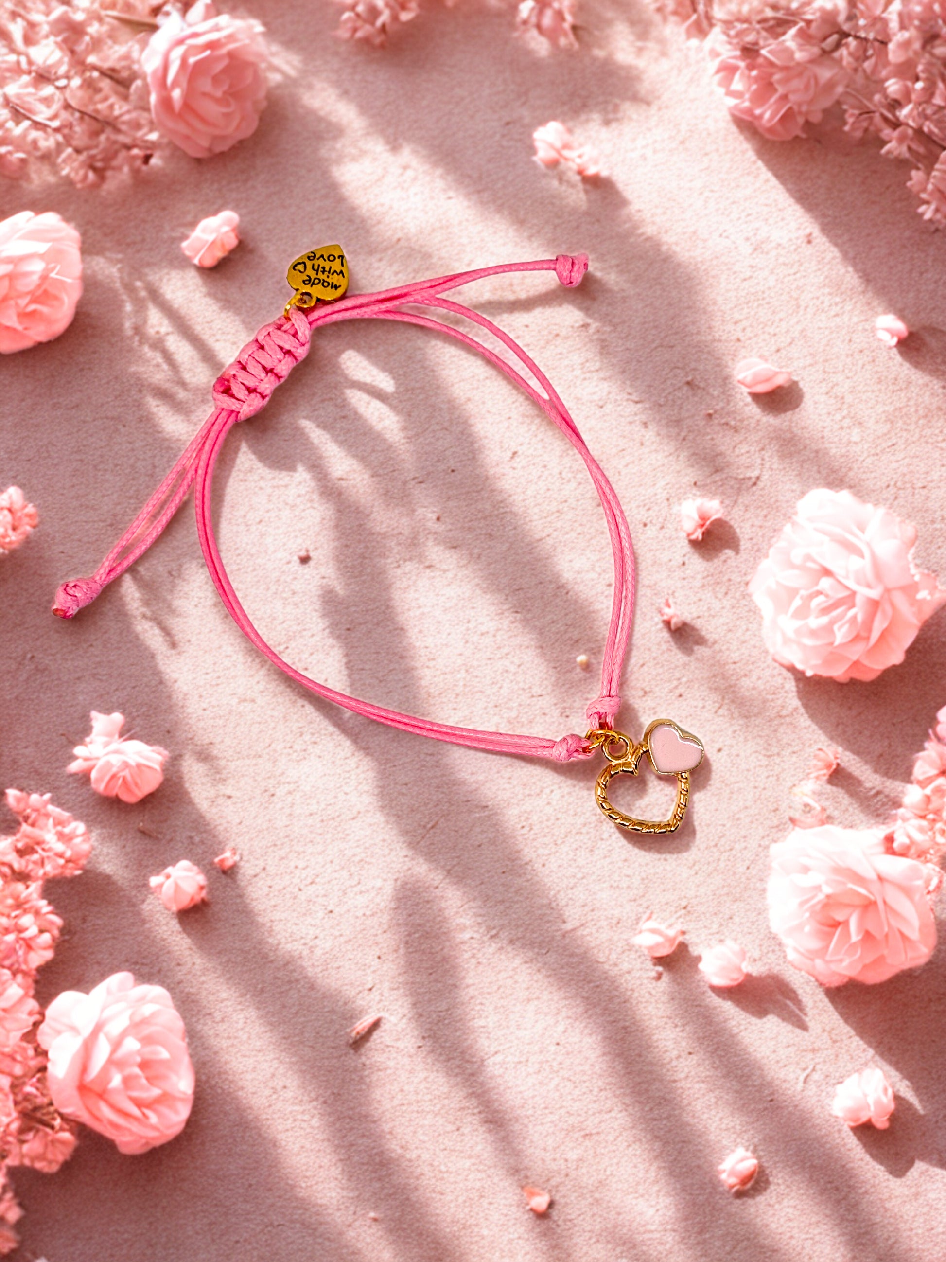 Pink bracelet with gold heart charms on a pink floral background