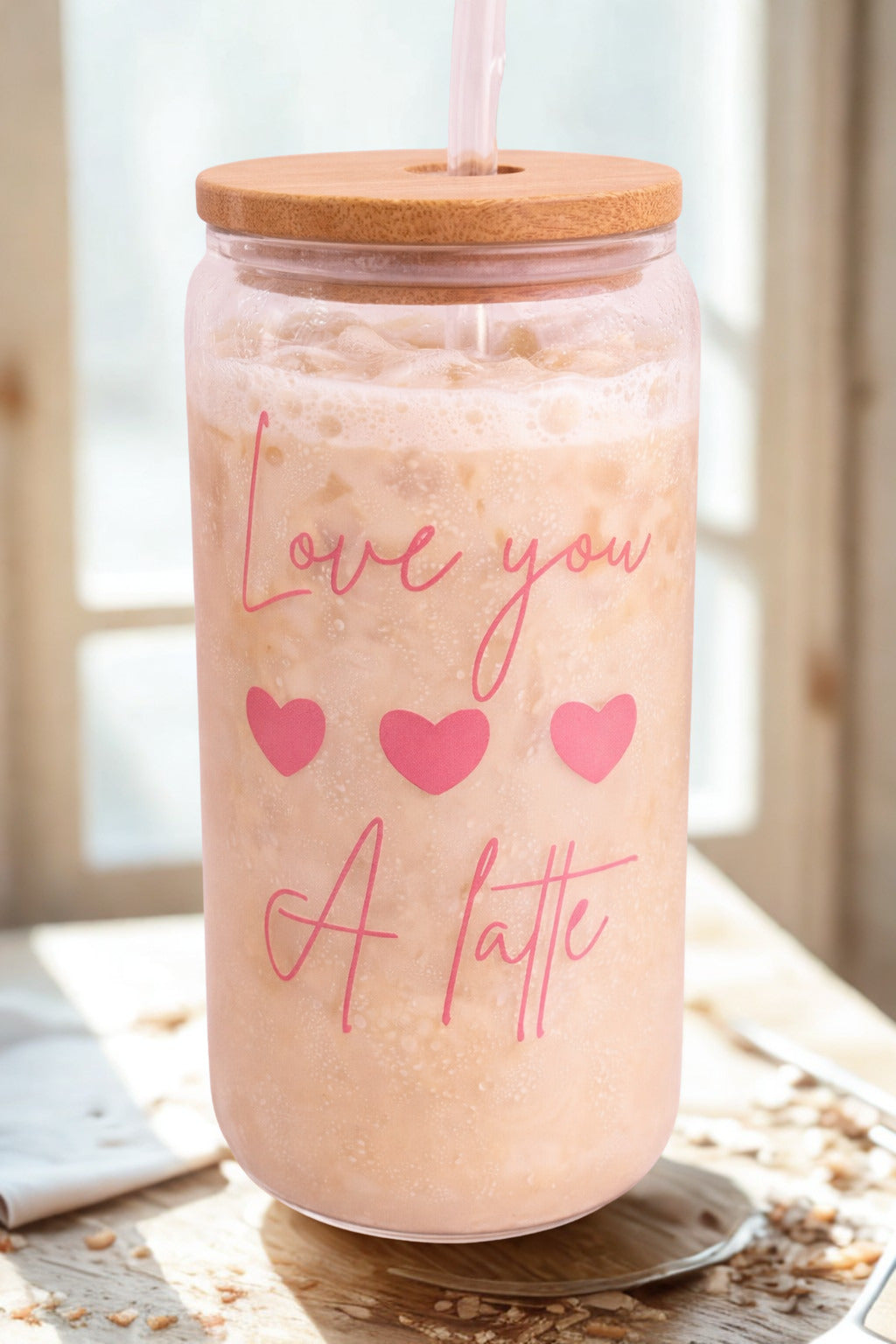 Glass of iced coffee with a straw and wooden lid, featuring 'Love you a latte' text.