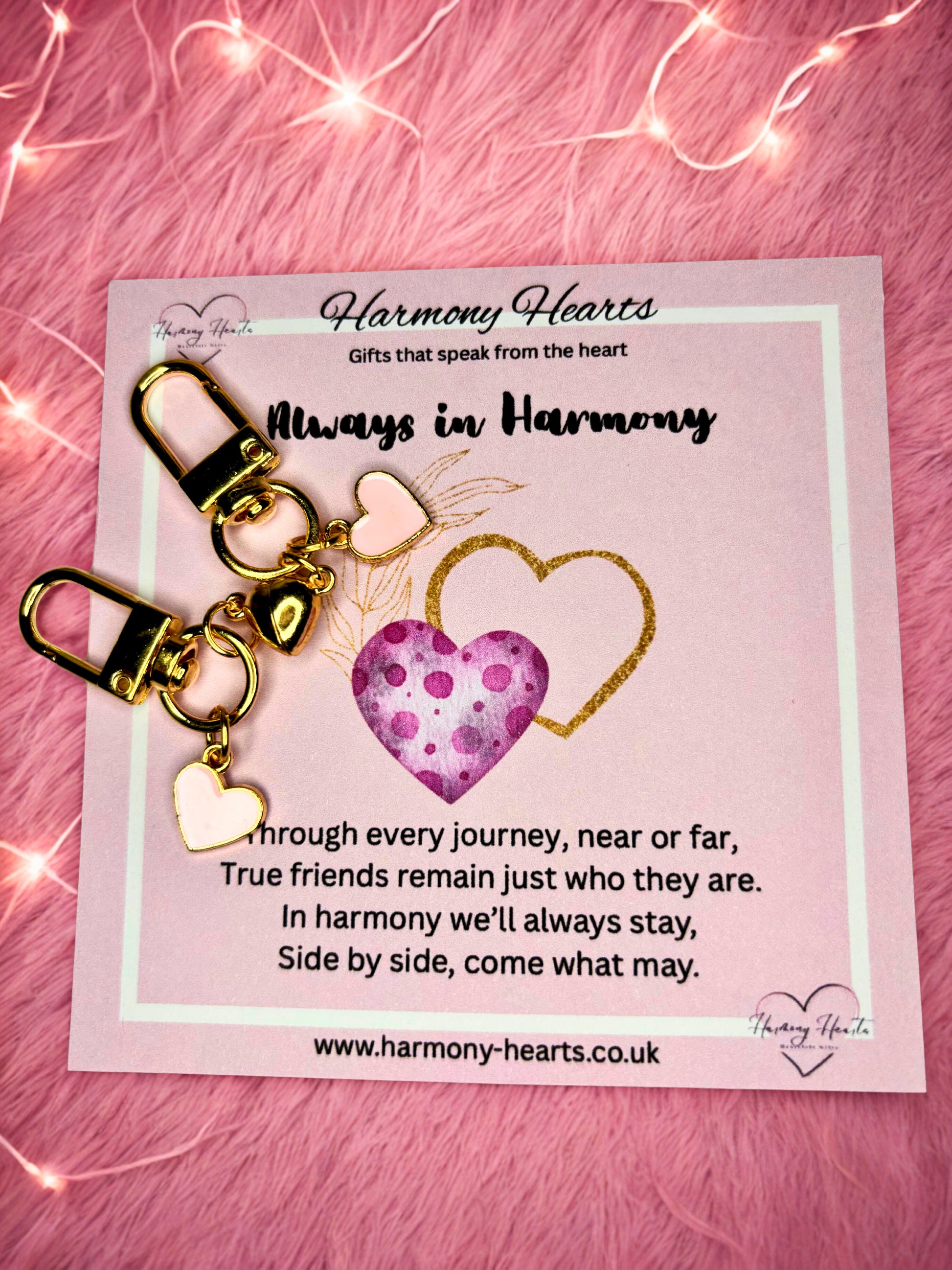 Heart-shaped keychain with gold accents on a pink card with text, against a pink textured background.