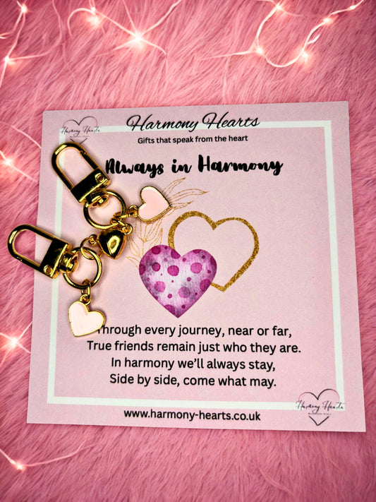 Heart-shaped keychain with gold accents on a pink card with text, against a pink textured background.