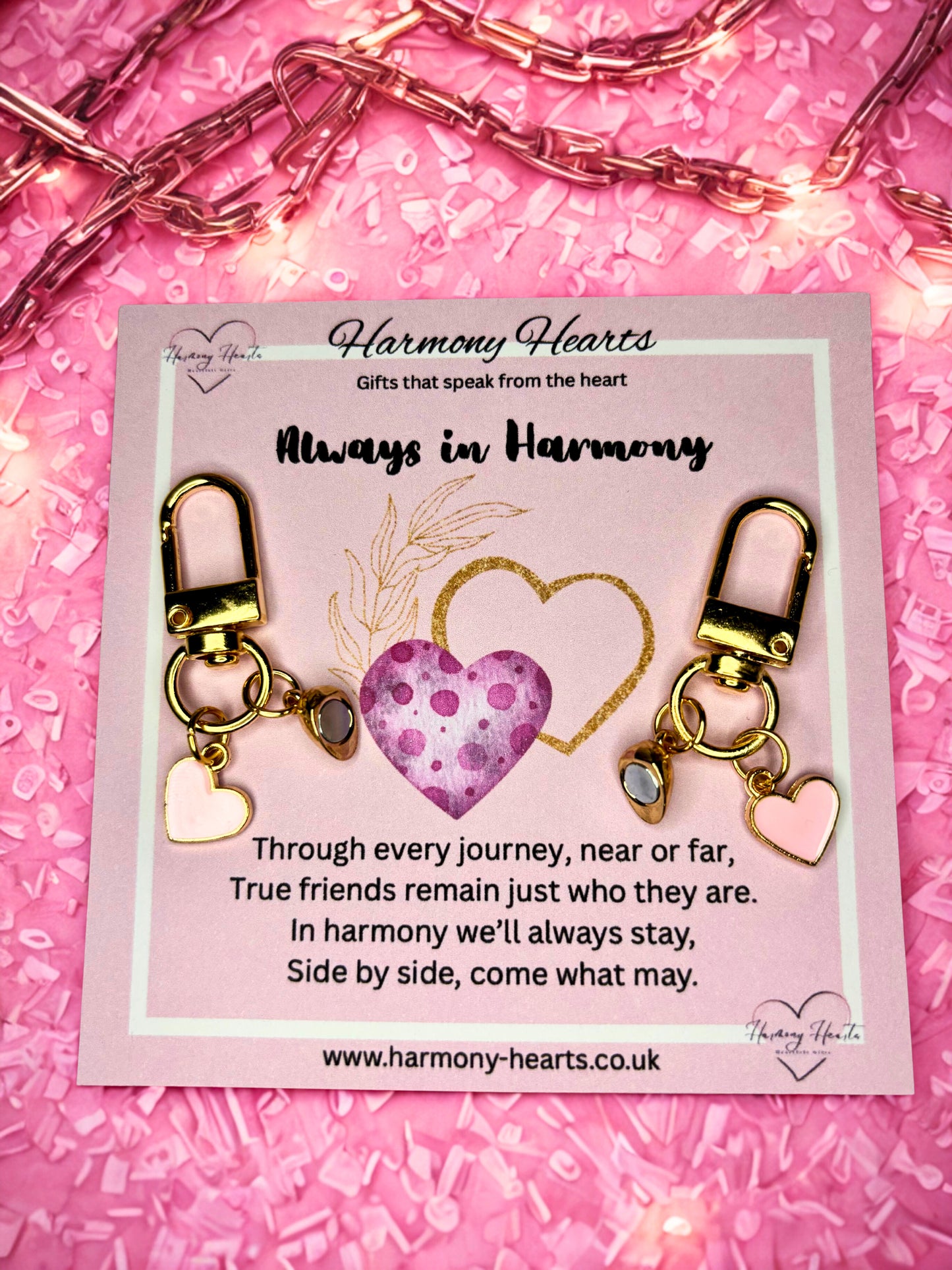 Harmony Hearts keychain set on a pink card with decorative lights and confetti.