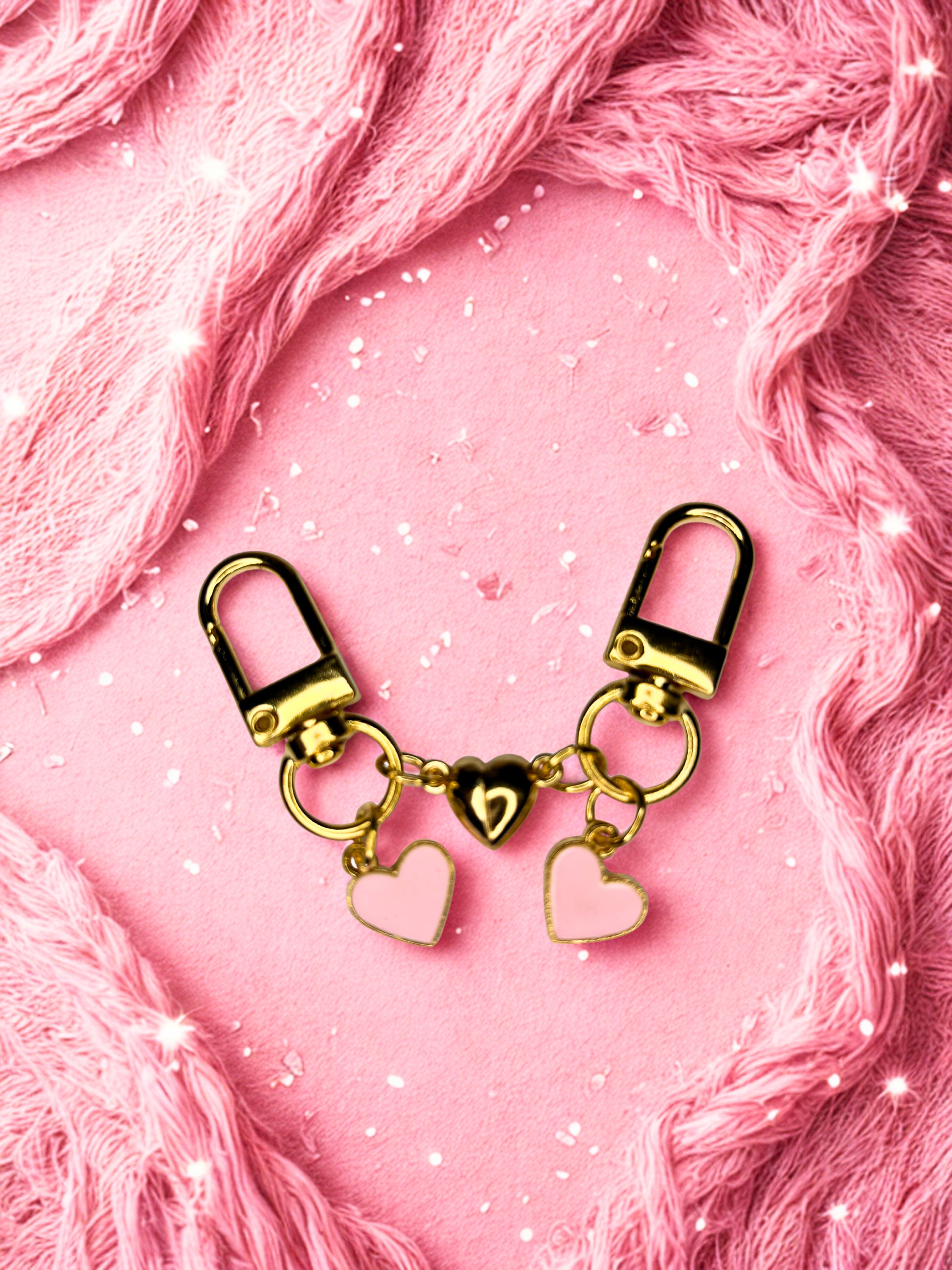 Gold keychain with heart charms on a pink textured background