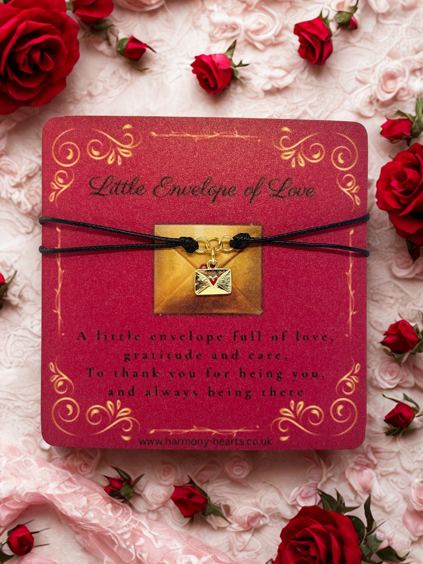 Red card with gold envelope charm and rose petals on a floral background