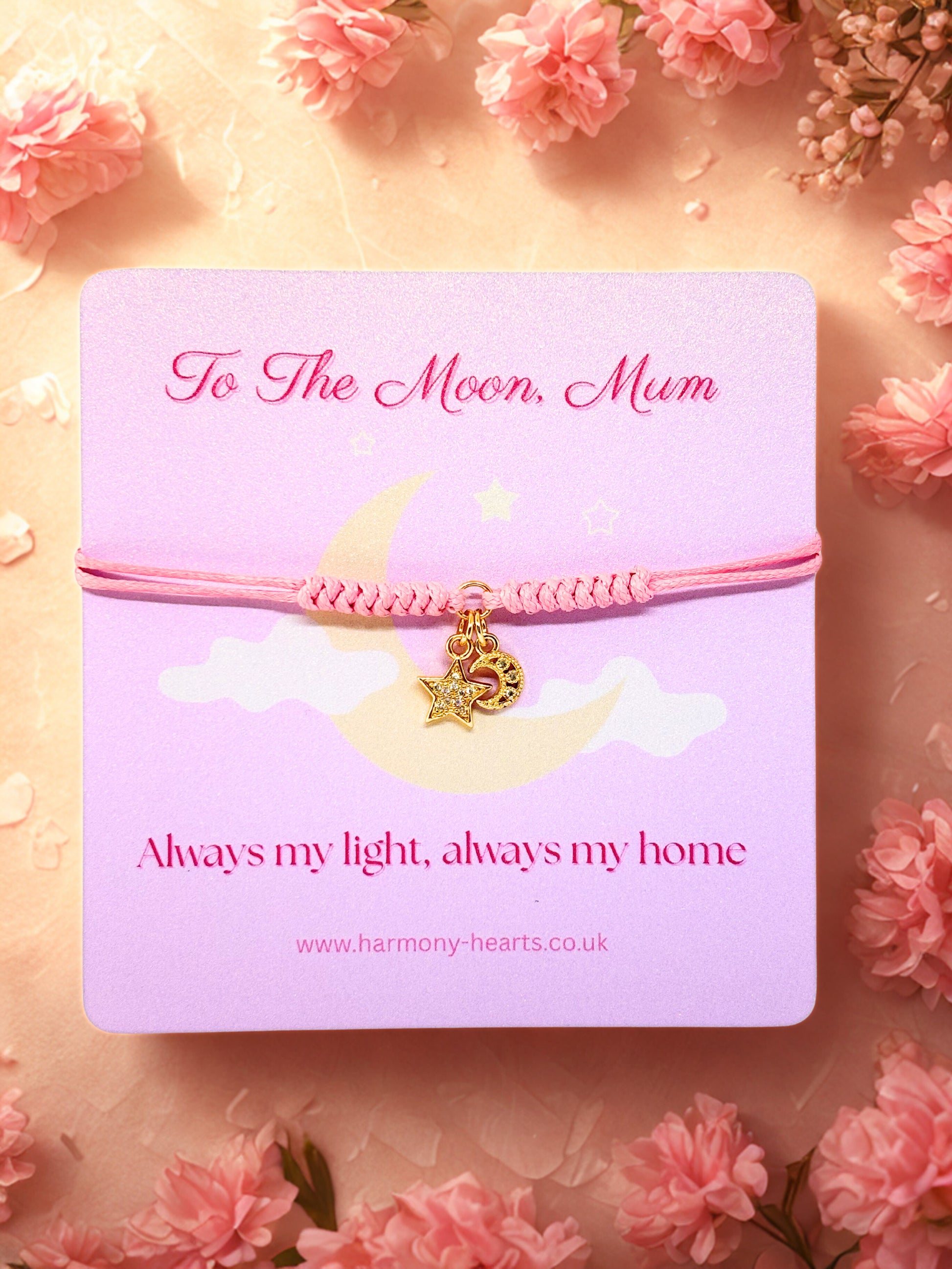 Pink bracelet with moon and star charms on a pink card with floral background
