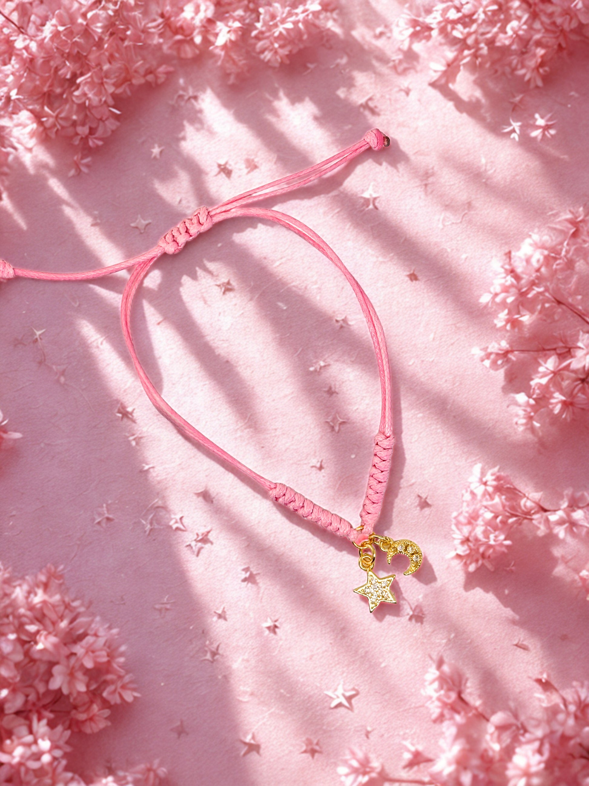 Pink bracelet with moon and star charms on a pink floral background
