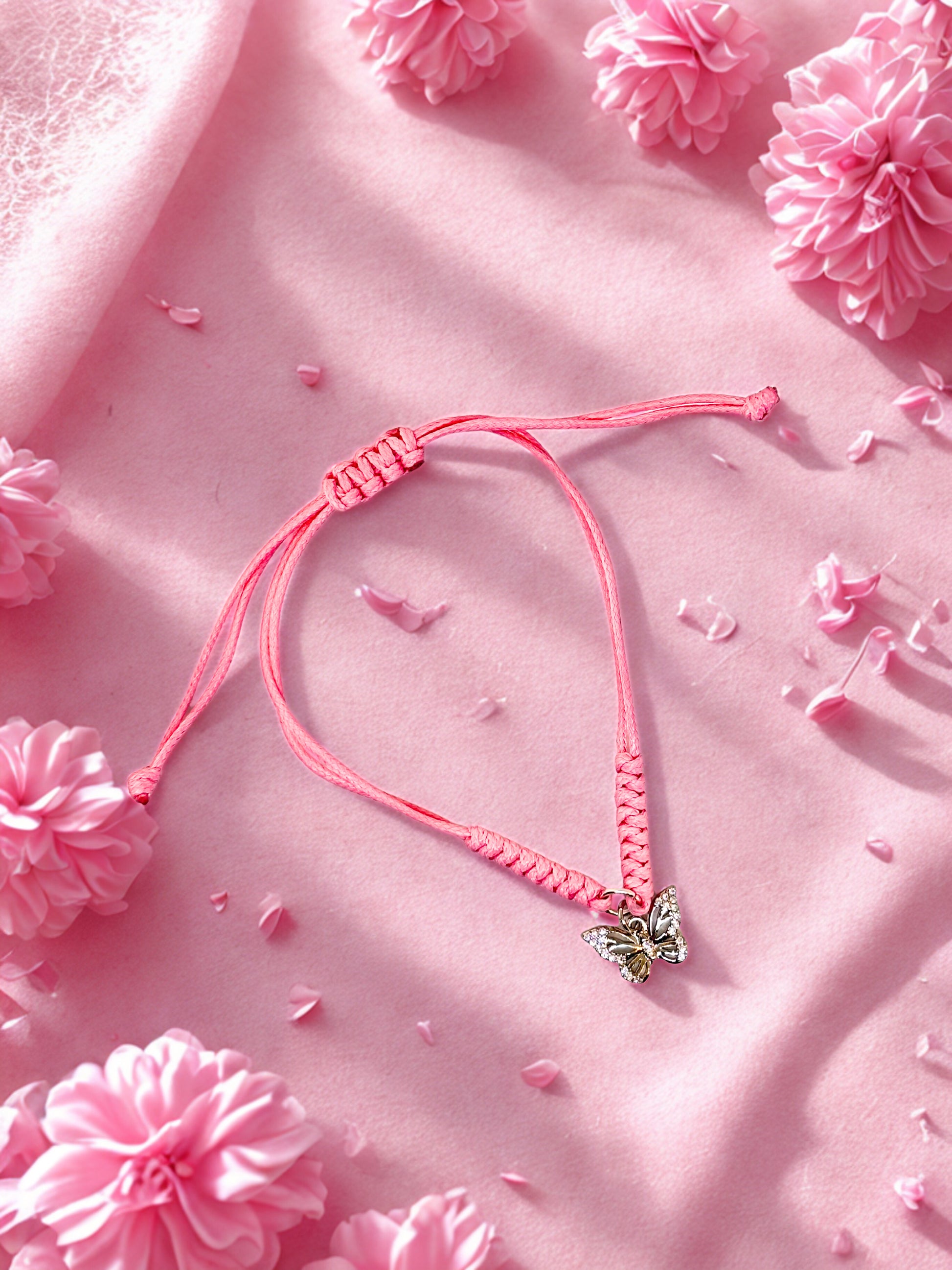Pink braided bracelet with a butterfly charm on a pink floral background