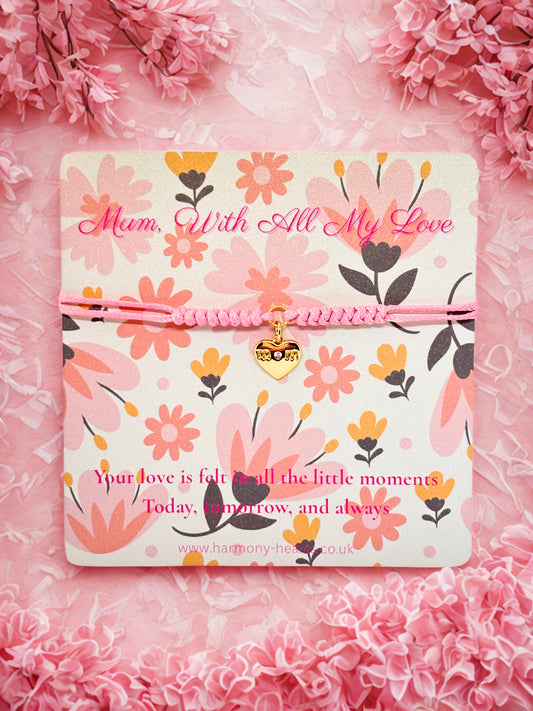 Floral-patterned card with 'Mum, With All My Love' text with a pink cord heart bracelet on a pink floral background